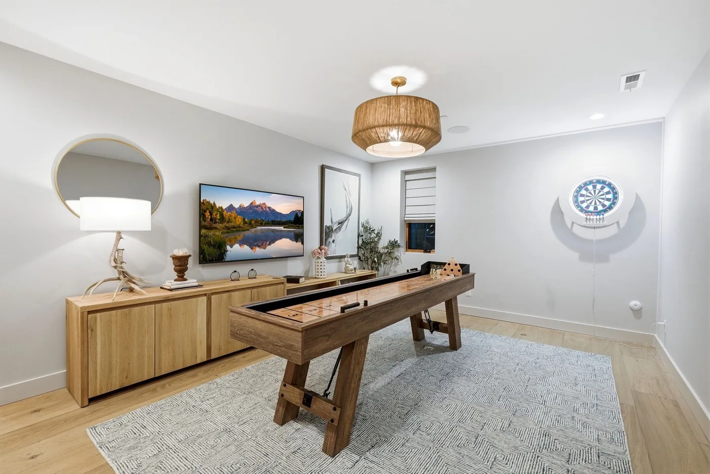Una sala de juegos luminosa cuenta con una mesa de tejo de madera y una diana en la pared.