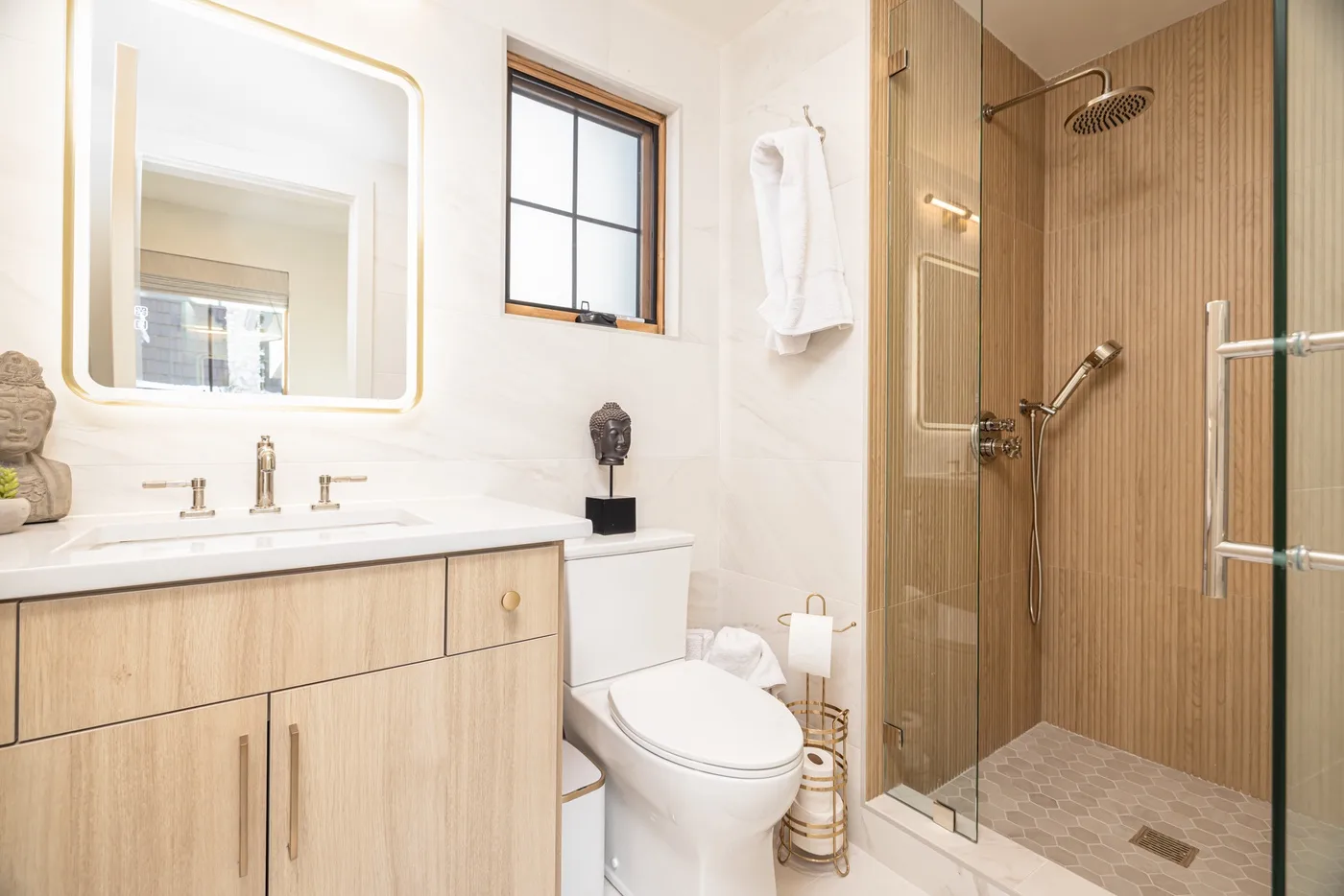 Un baño luminoso con mueble de madera, inodoro y ducha con paneles de vidrio.