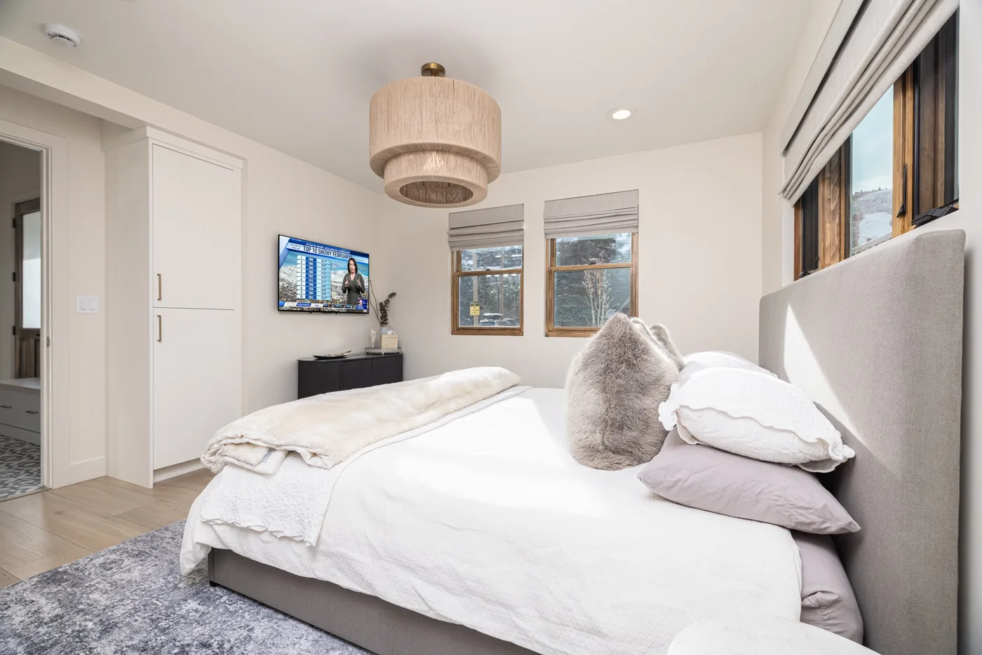 Un dormitorio luminoso con una cama bien hecha y ventanas que dan al exterior.