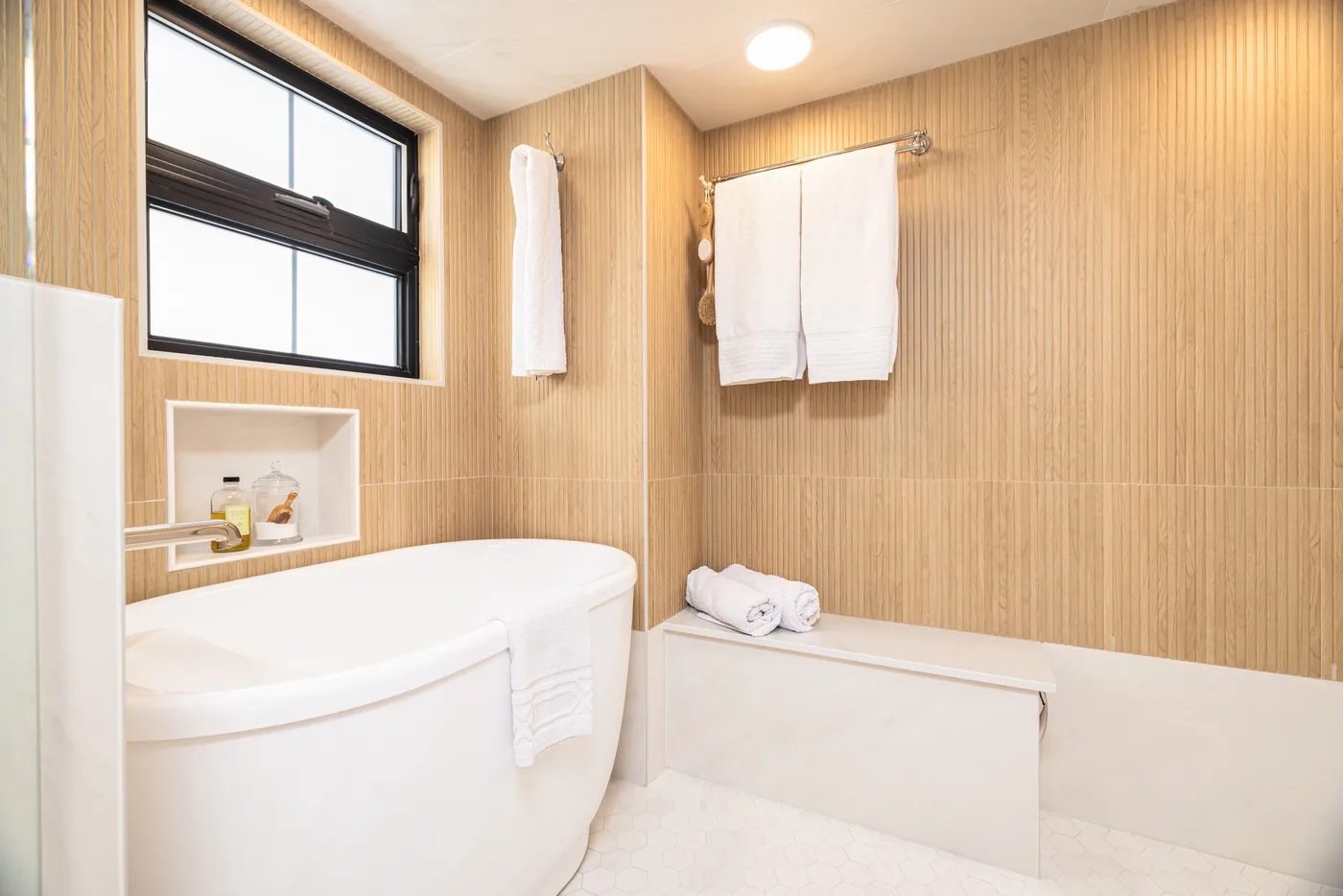 Un baño luminoso con bañera, toallas y una ventana.