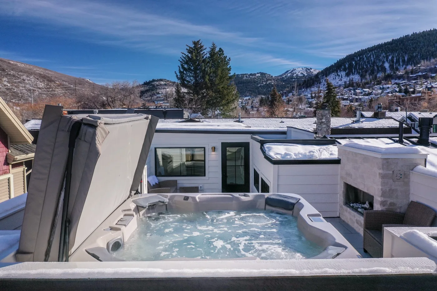 Una bañera de hidromasaje al aire libre está en una terraza con vistas a las montañas.
