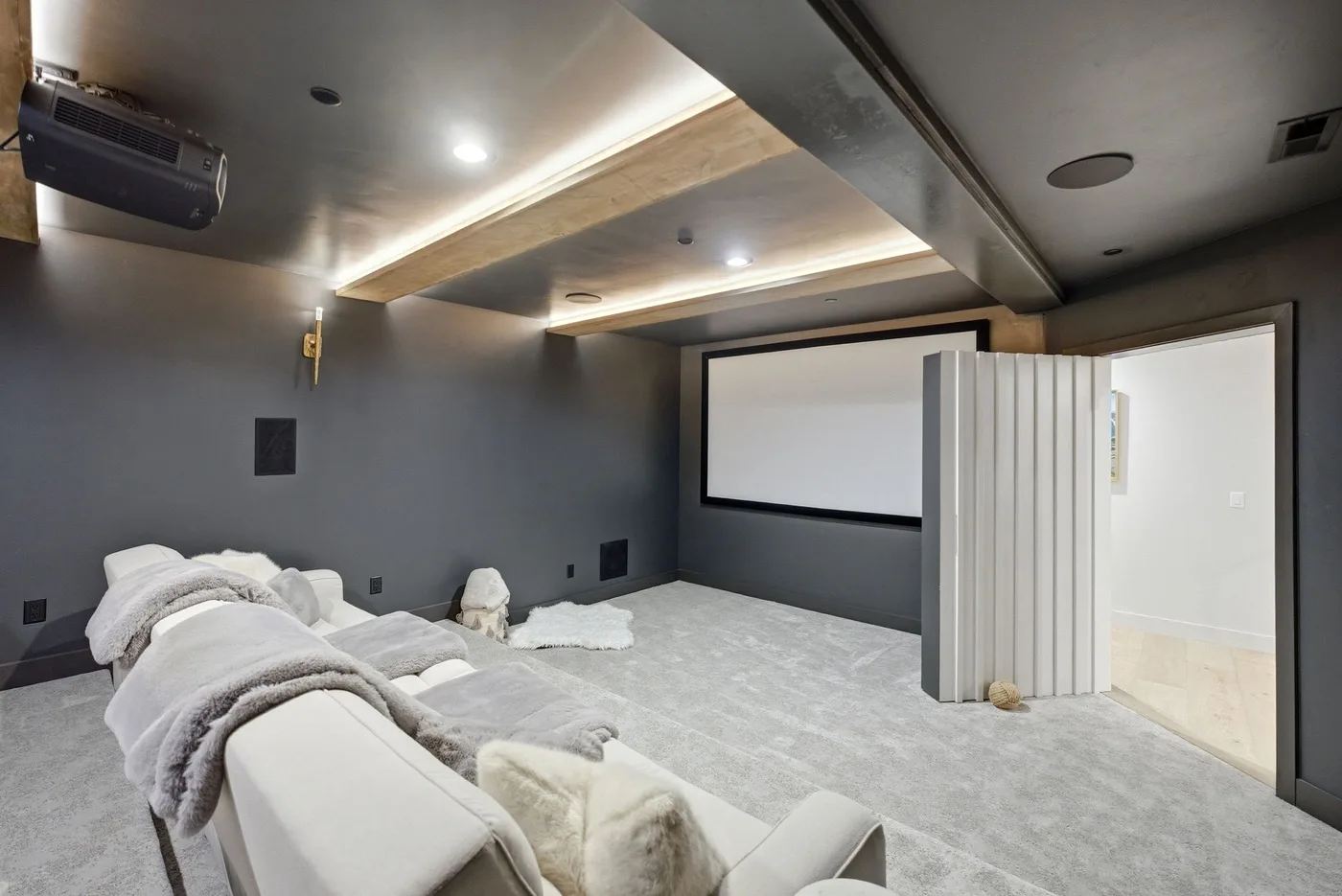 Una sala multimedia con una pantalla de proyección grande y asientos acolchados.