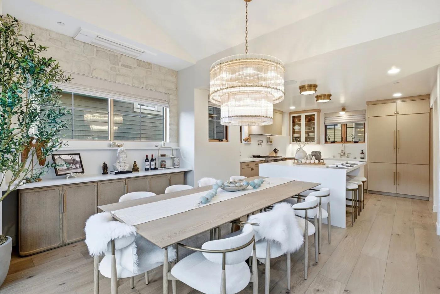 Una luminosa cocina-comedor de espacio abierto con una mesa larga y lámparas colgantes.