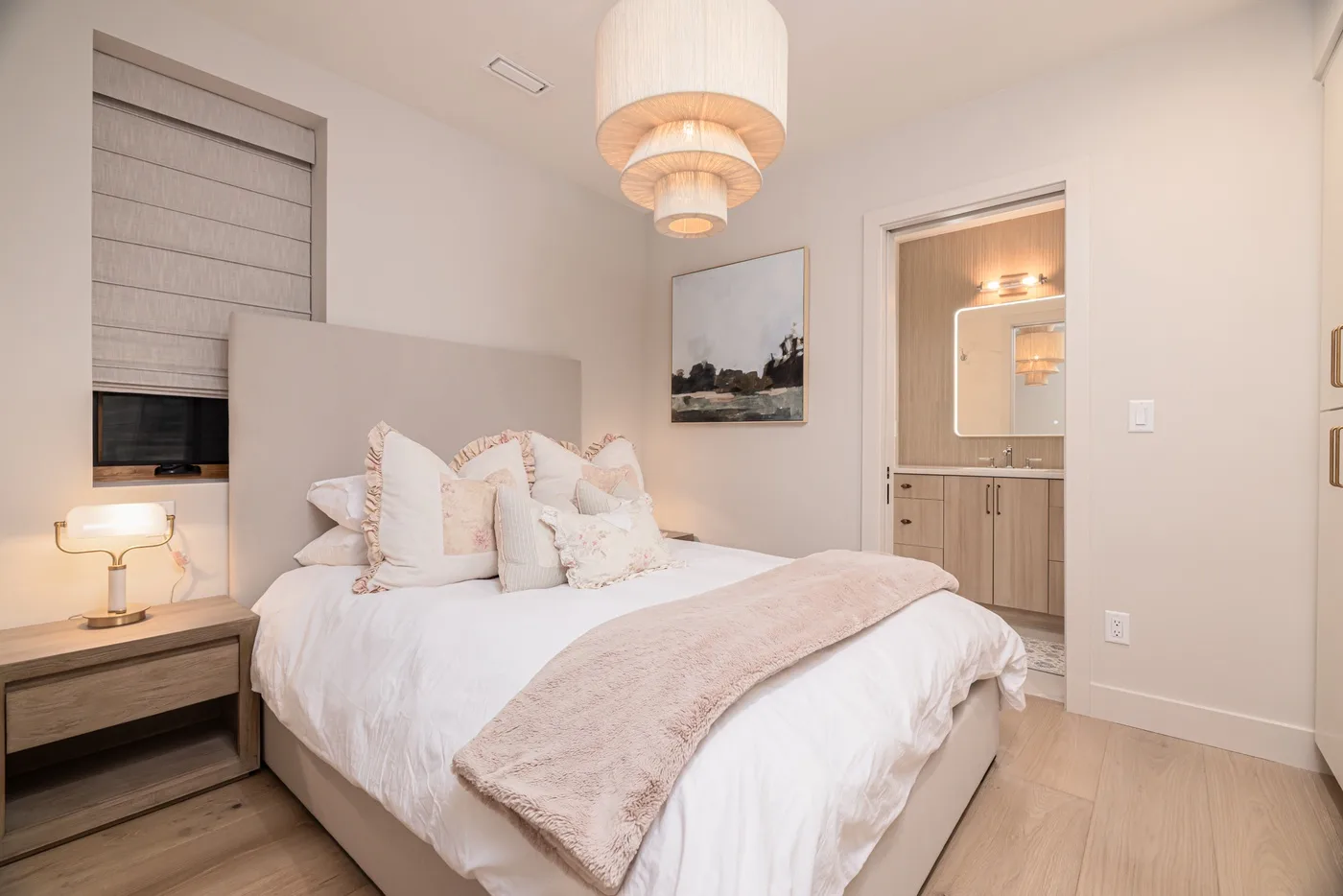 Un dormitorio luminoso con una cama tendida y una iluminación suave.