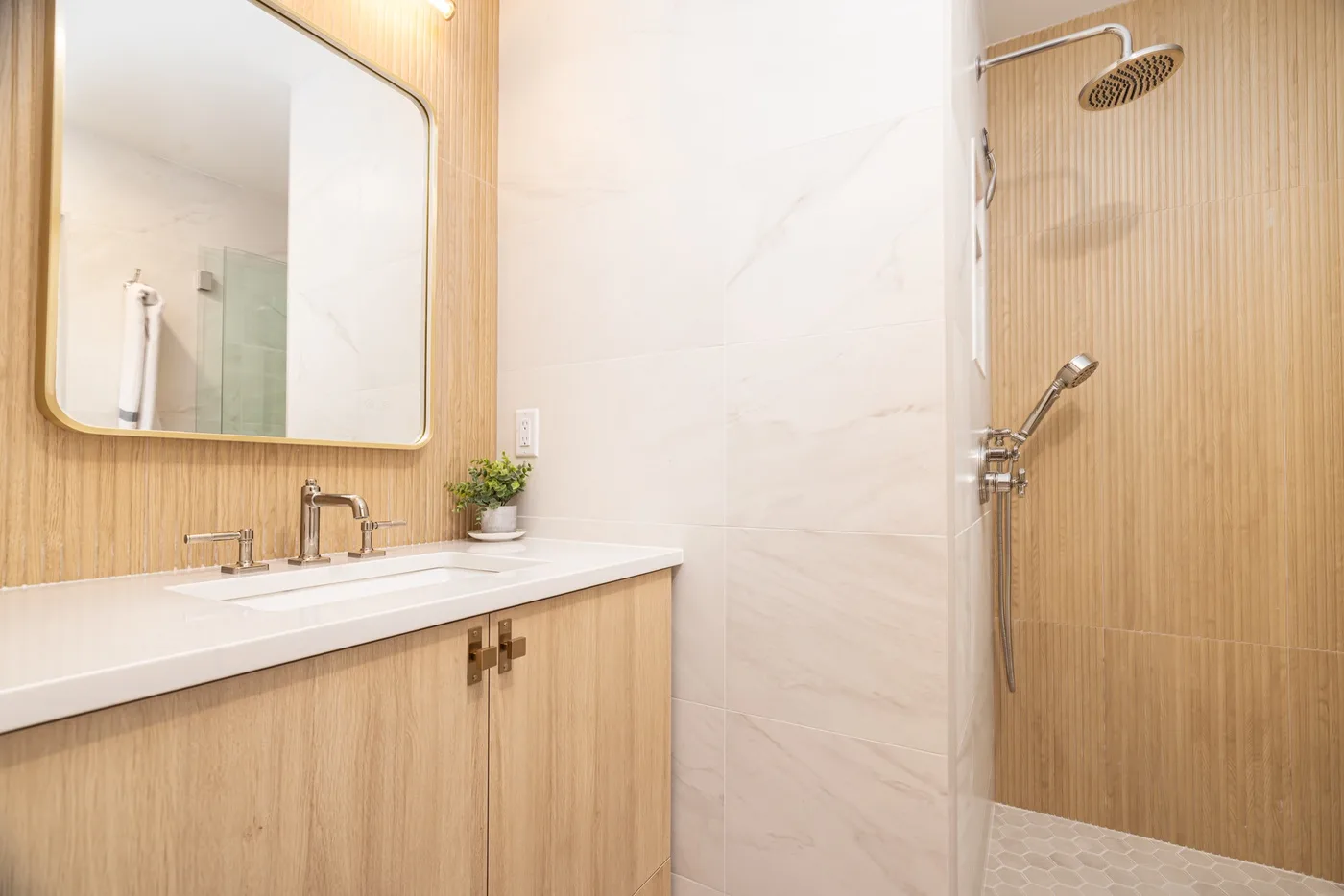 Baño luminoso con un tocador largo y una ducha con mampara de vidrio.