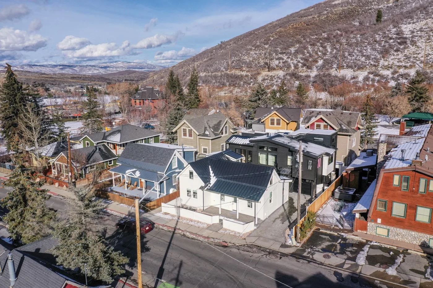 Vista aérea de un barrio residencial con casas al pie de una ladera nevada.