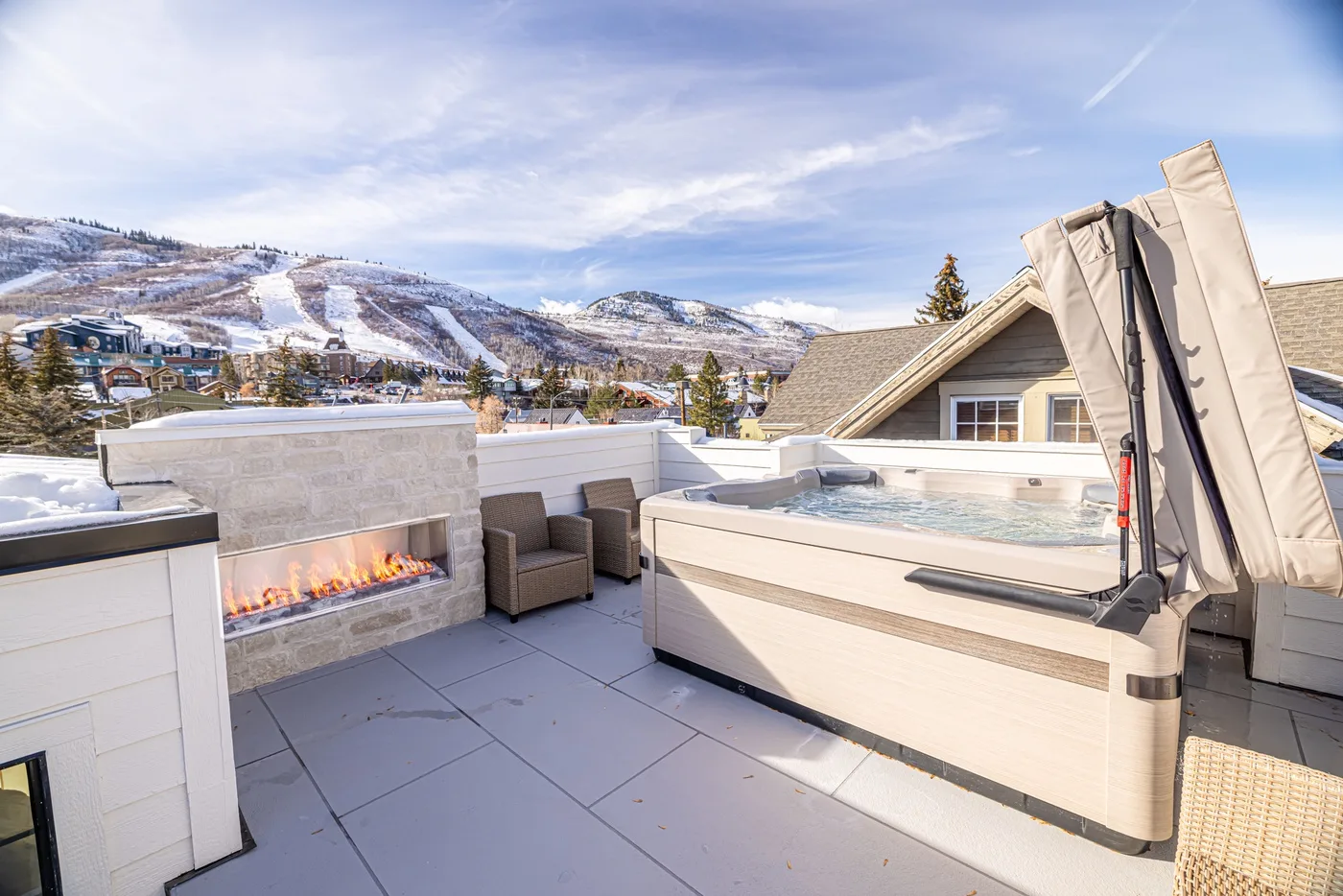 A rooftop terrace features a hot tub, outdoor seating, and mountain views.