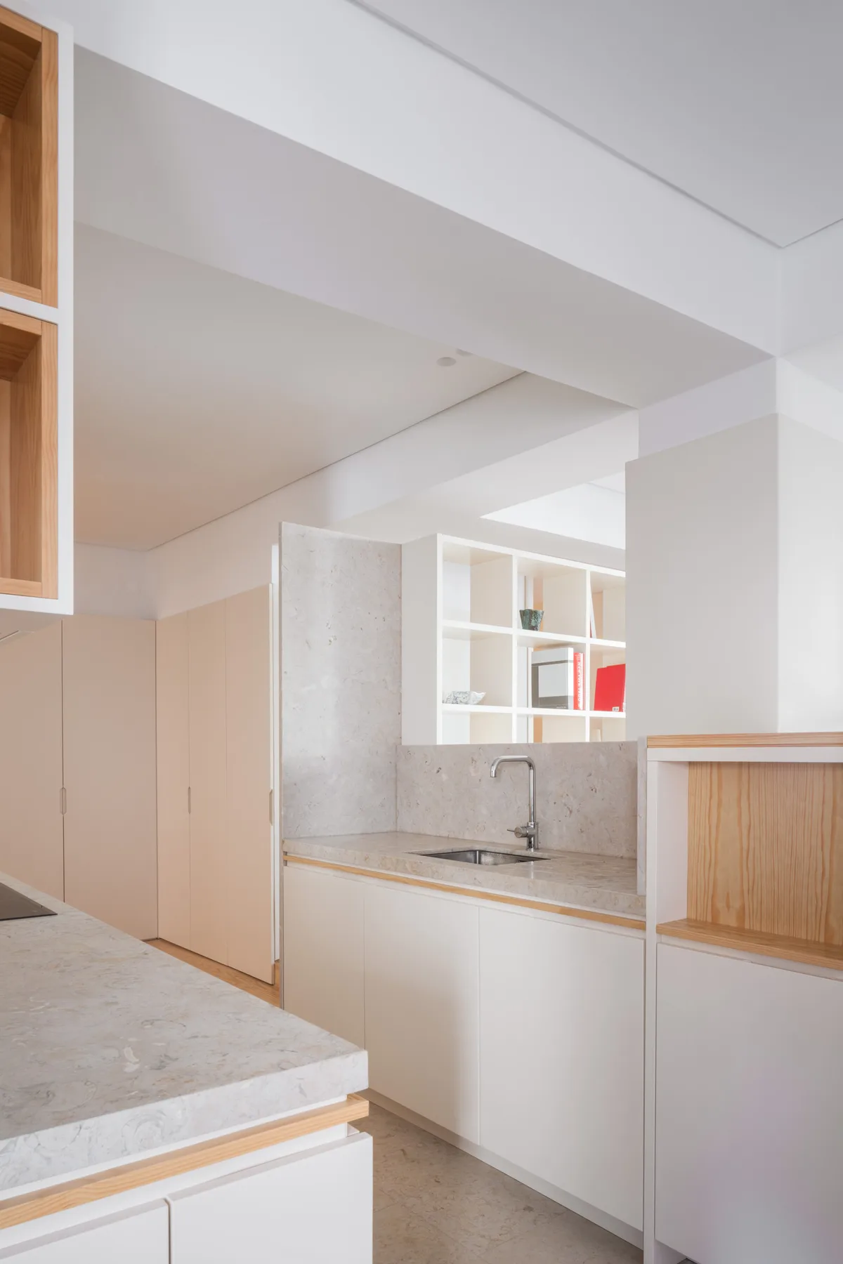 A bright modern kitchen with pale cabinetry and a stone countertop.