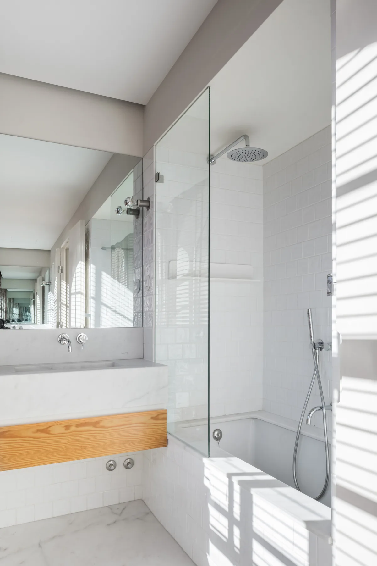 A bright bathroom with a glass-enclosed shower and a long vanity.