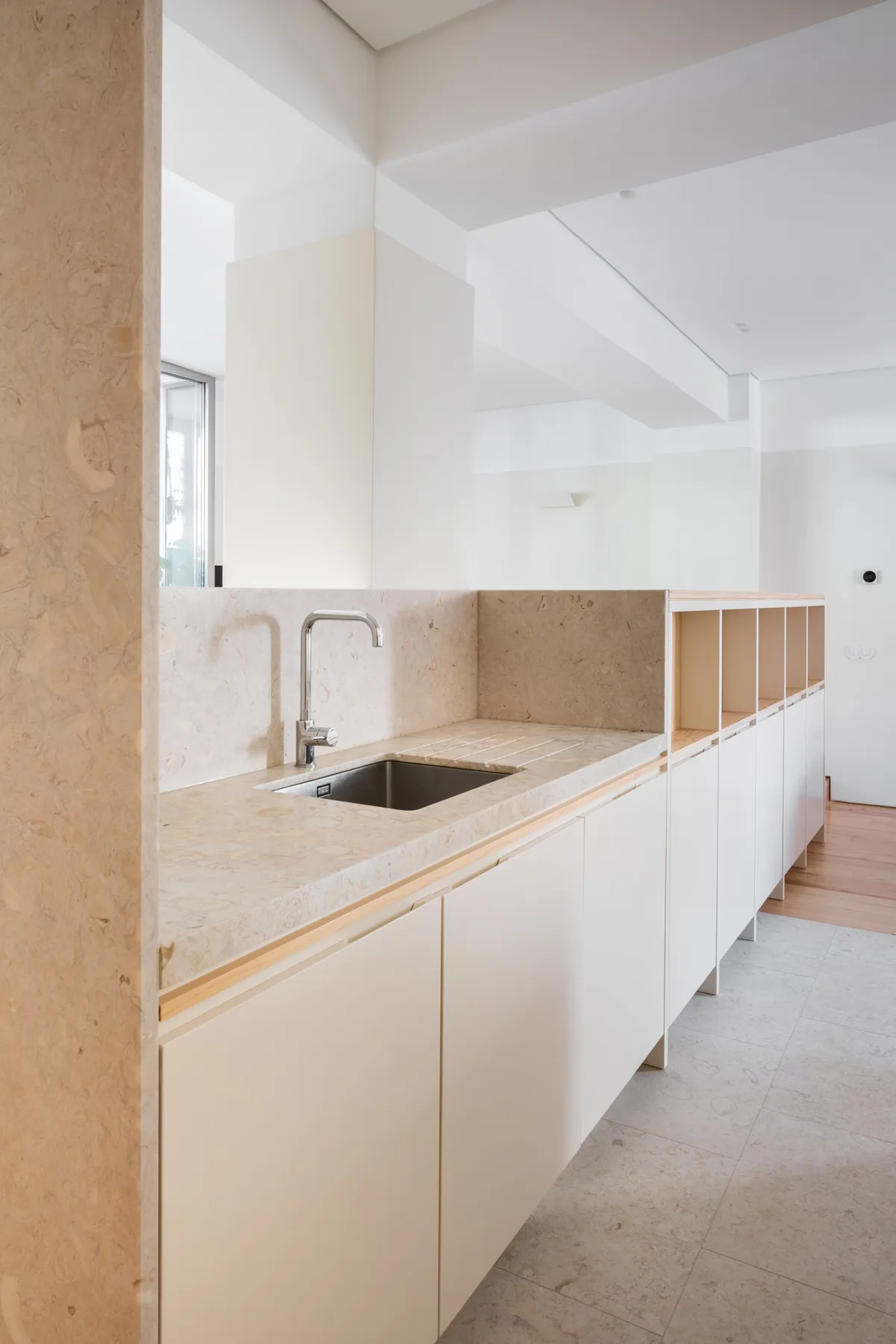 A bright kitchen with a long counter, sink, and white cabinets.