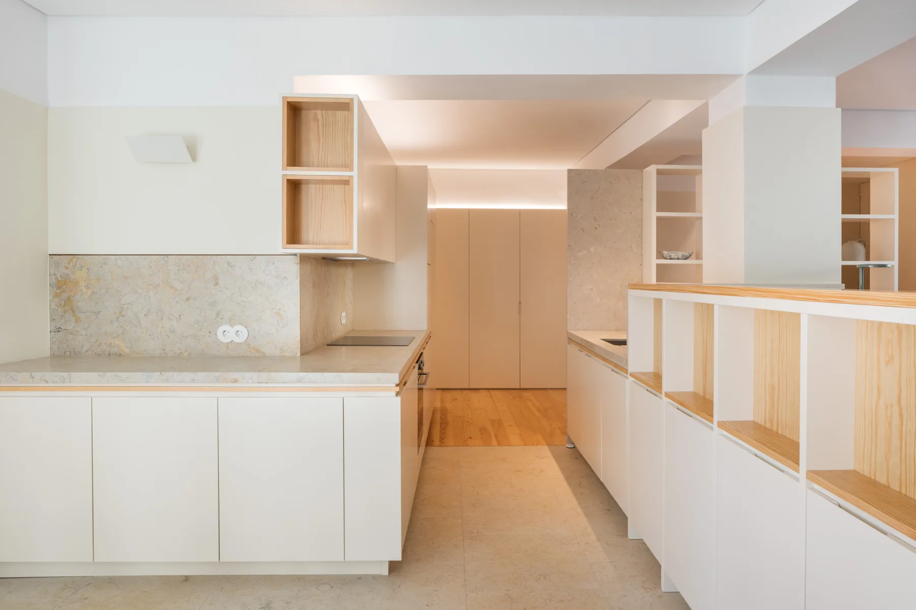Una cocina moderna con armarios claros y un pasillo central.