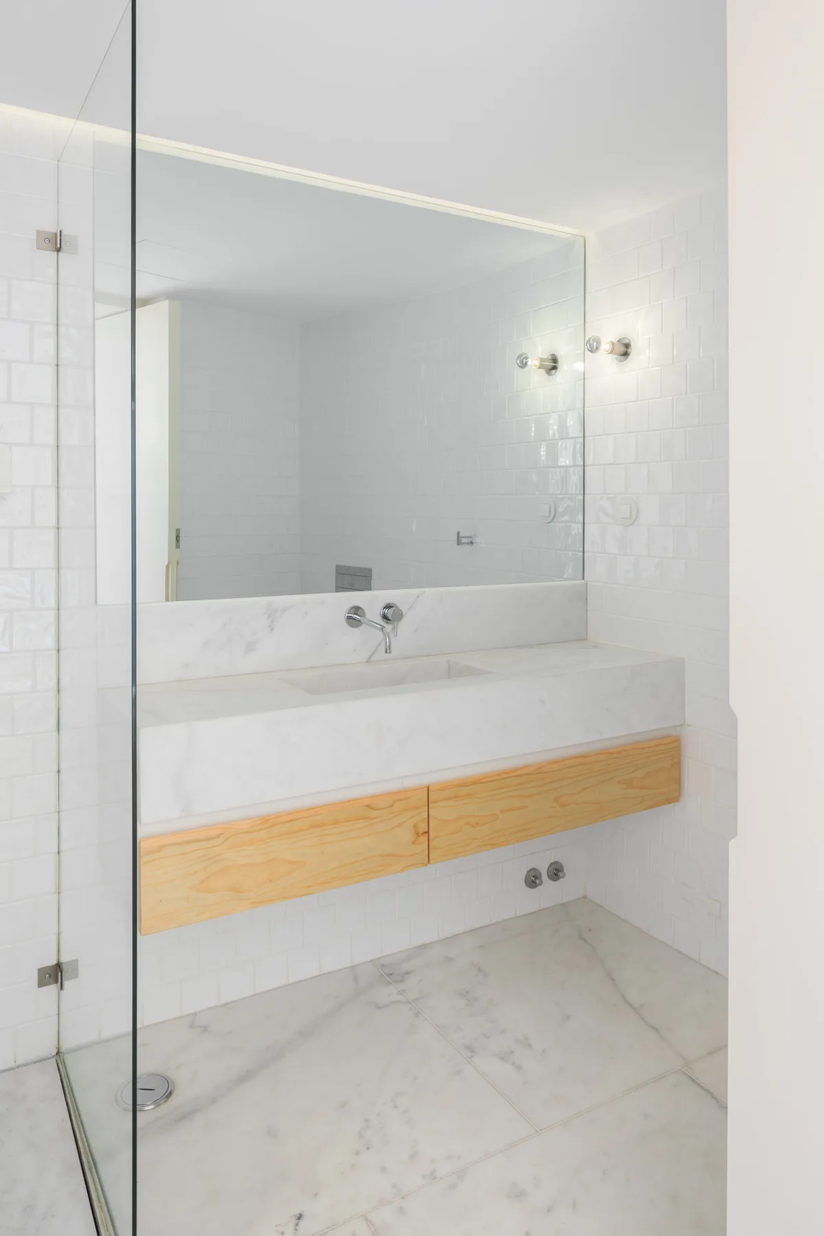 A bright bathroom with a wide mirror above a wall-mounted vanity.