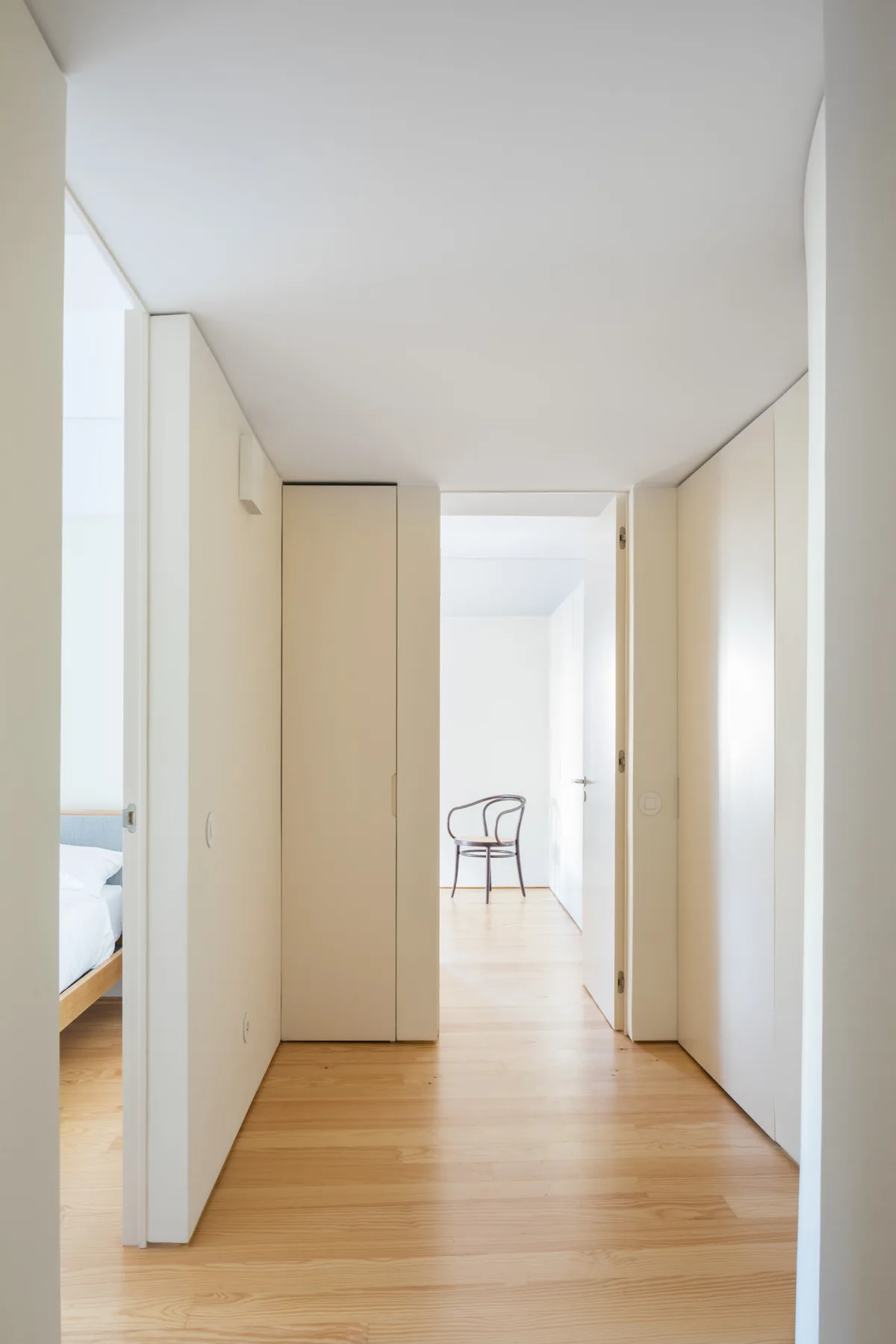 A bright apartment hallway with light wood flooring and open doorways.