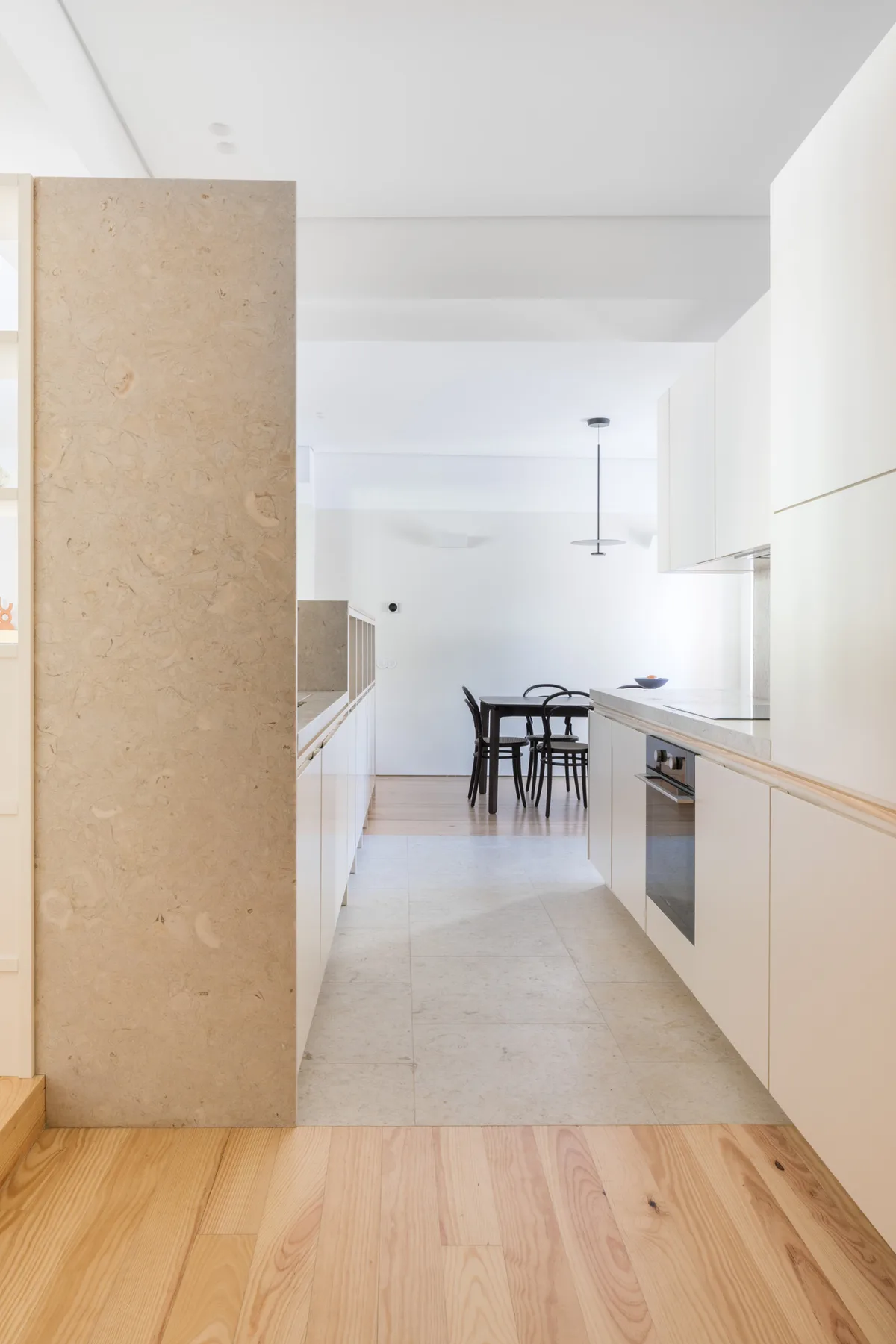 A bright kitchen with white cabinets and a dining table at the far end.