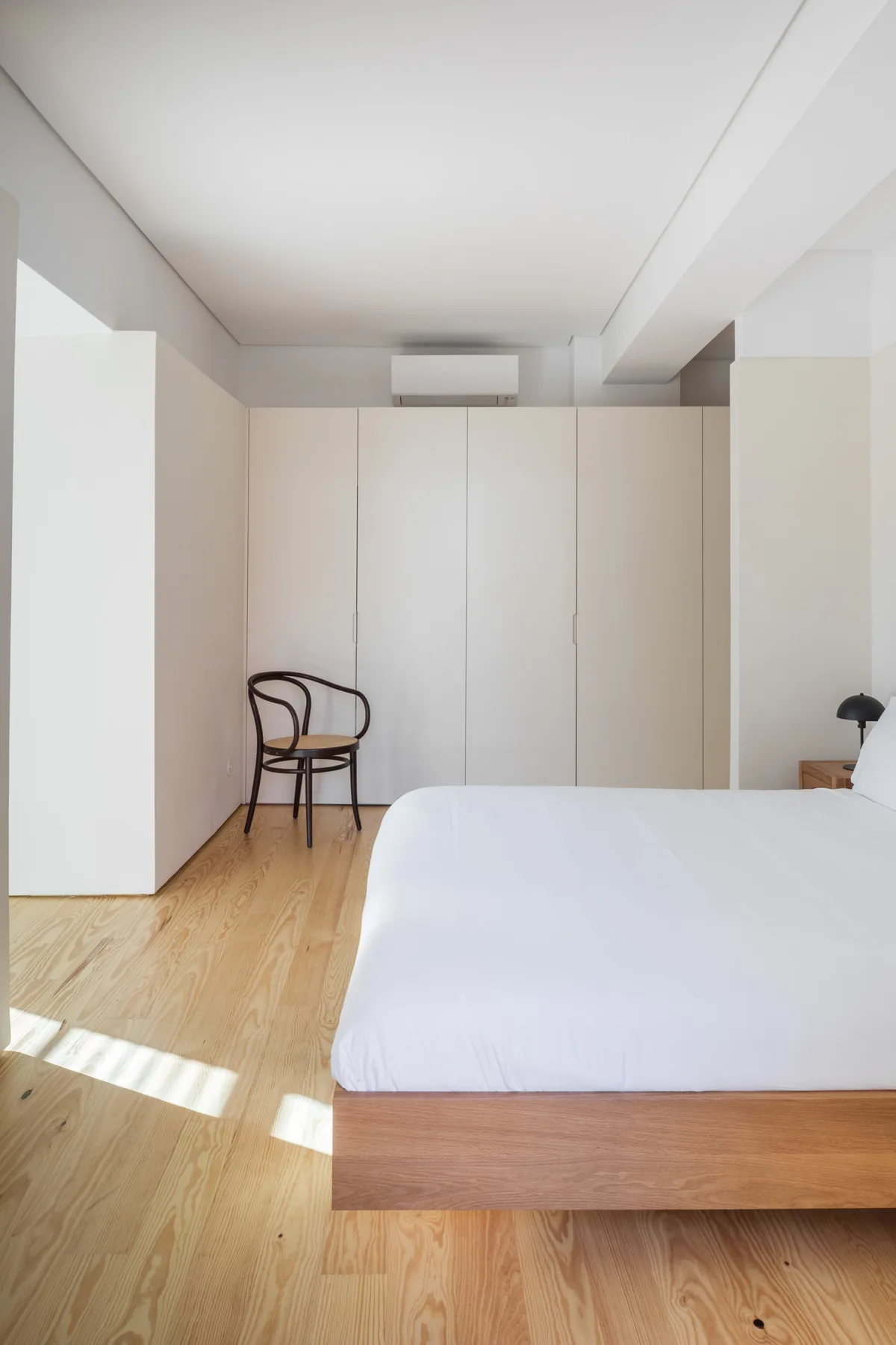 A bedroom with a bed, built-in storage, and a wooden chair.