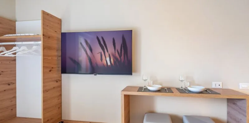 Un comedor con una mesa de madera puesta debajo de una pantalla montada en la pared.