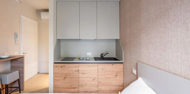 Una cocina compacta con gabinetes de madera clara y una encimera oscura.
