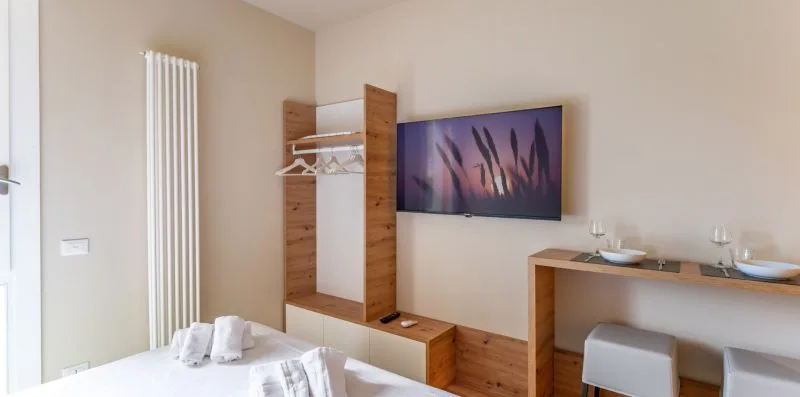Un dormitorio con un televisor montado en la pared y una cama en primer plano.