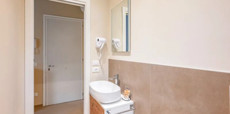 A bathroom vanity with a vessel sink and mirror beside an open doorway.