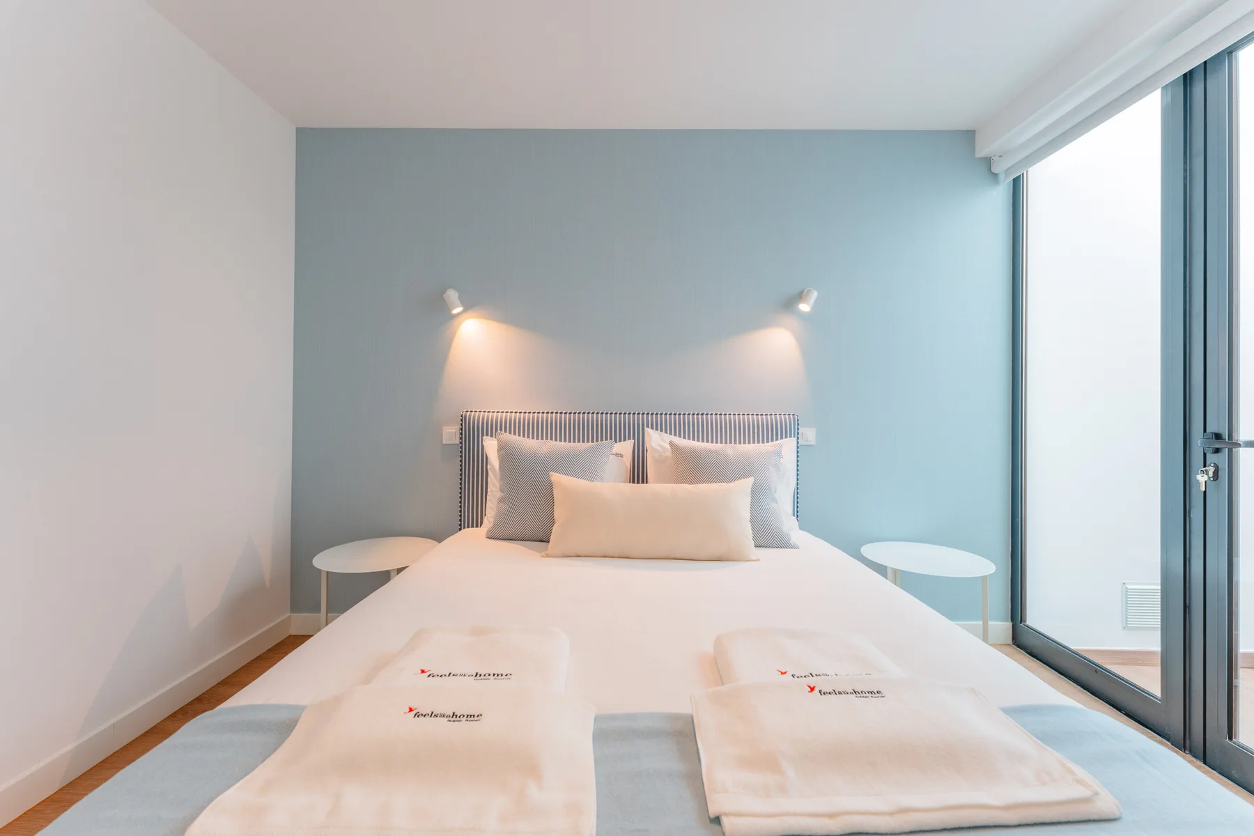 A bright bedroom with a large bed and a glass door opening onto a balcony.
