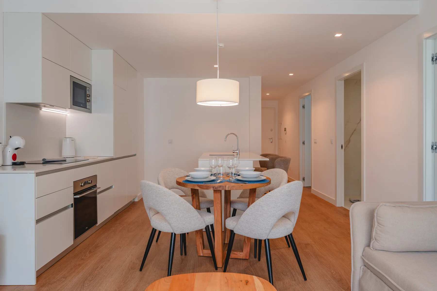 A dining area with a table and chairs beside a compact kitchen.