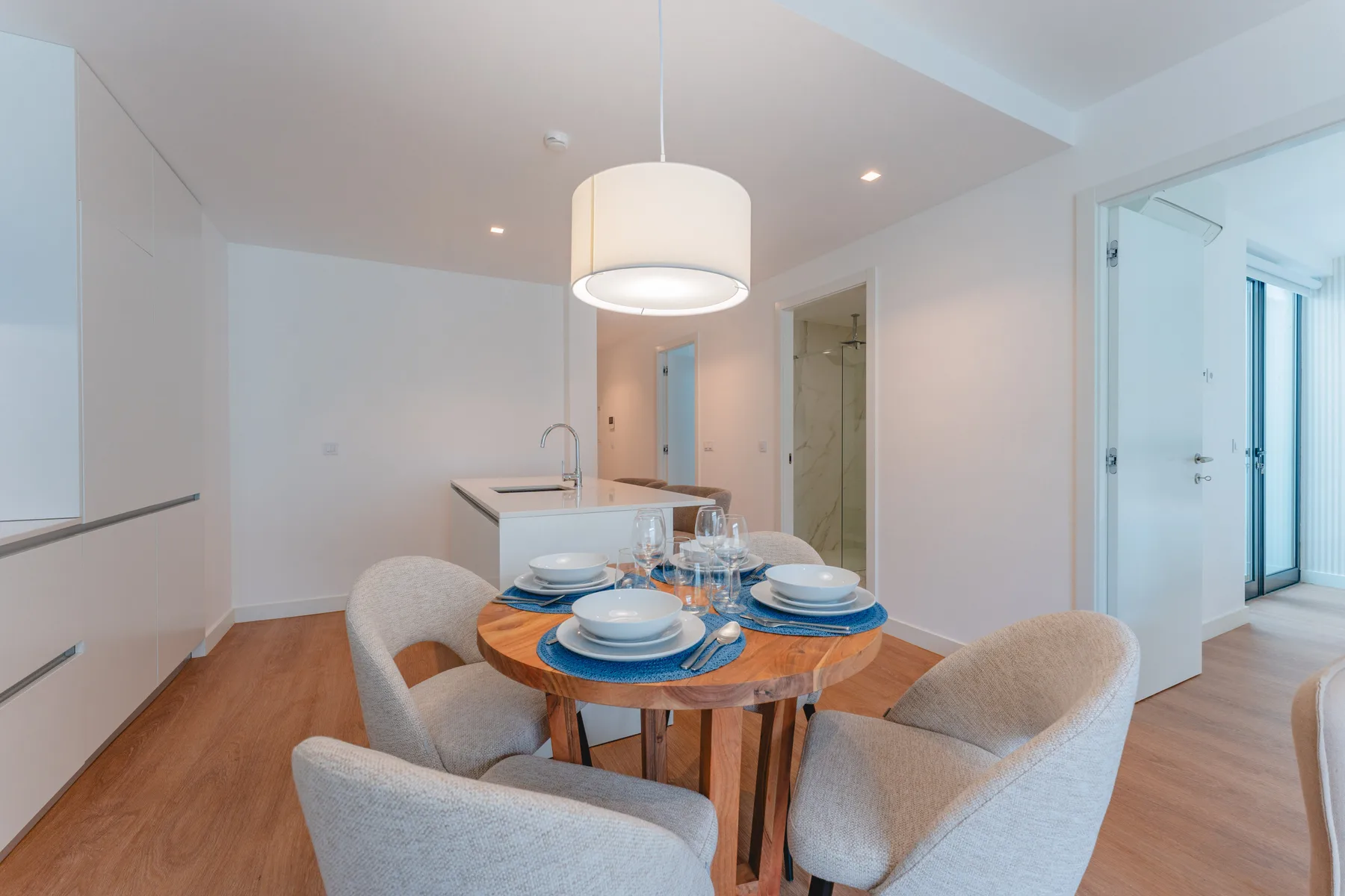 A dining area with a round table and upholstered seating beside a kitchen counter.