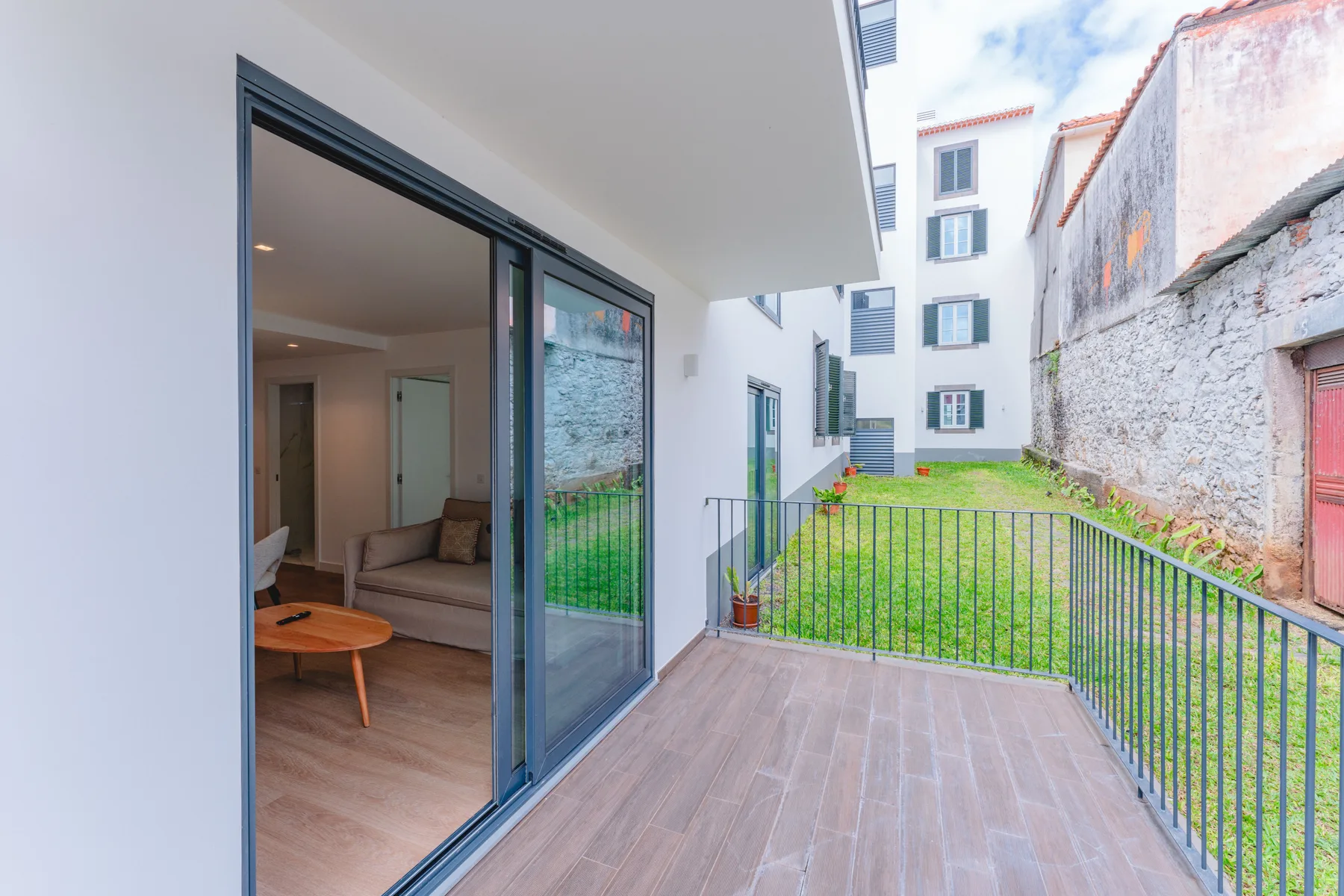 A balcony opens onto a small courtyard, with sliding glass doors beside it.