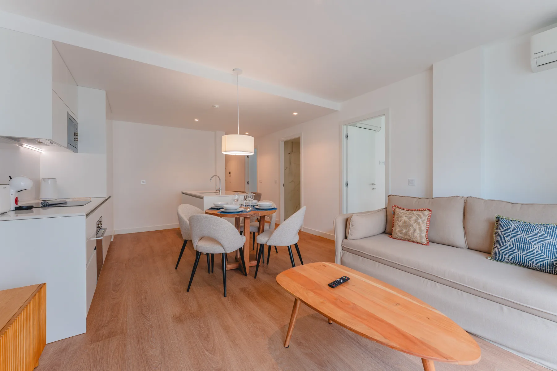 A bright living and dining area with seating, a dining table, and a wooden coffee table.