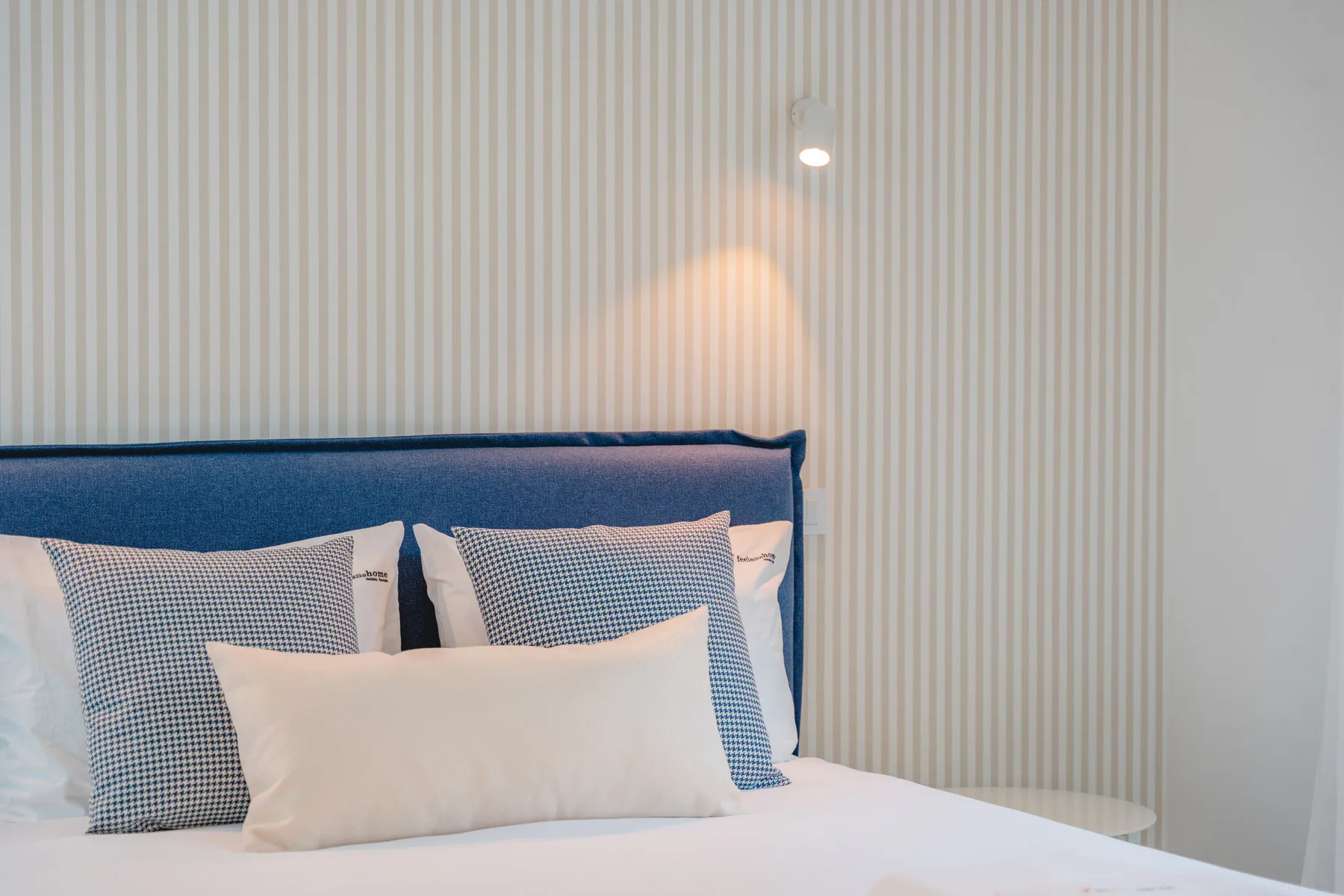 A bedroom with a bed and striped wallpaper.