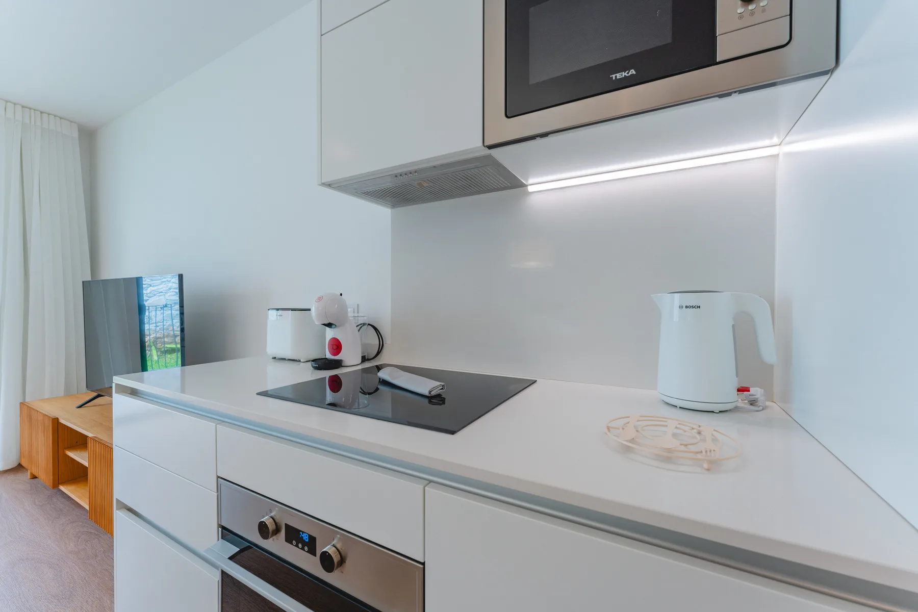 A bright kitchen with a cooktop and countertop appliances.