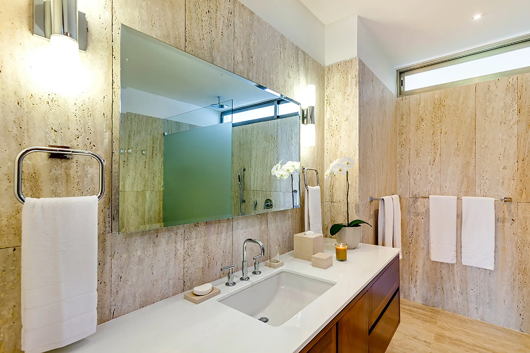 Un baño luminoso con un tocador largo, un lavabo empotrado y un espejo grande.