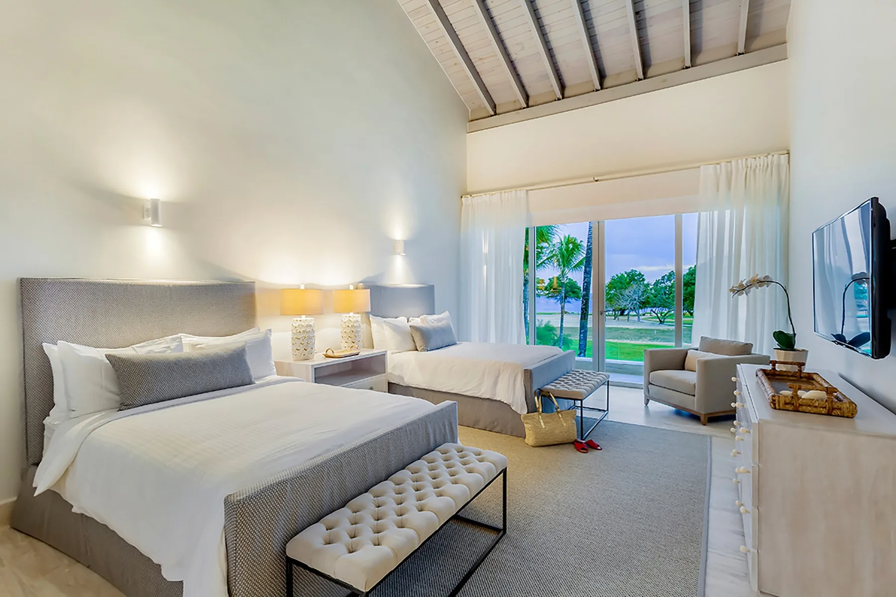 Un dormitorio luminoso con dos camas y grandes ventanas con vistas a zonas verdes.