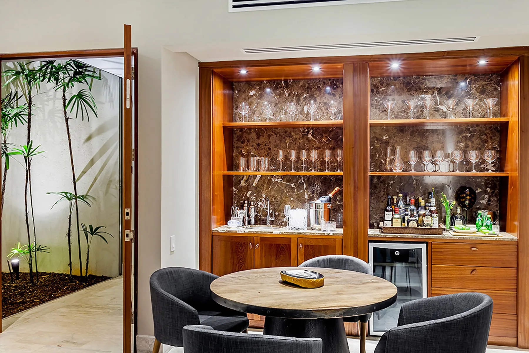 Un comedor con una mesa redonda y un mueble con puertas de vidrio que exhibe cristalería.