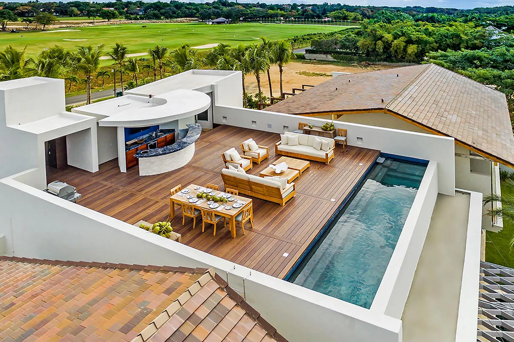 Una terraza en la azotea con asientos al aire libre, una mesa de comedor y una piscina estrecha.