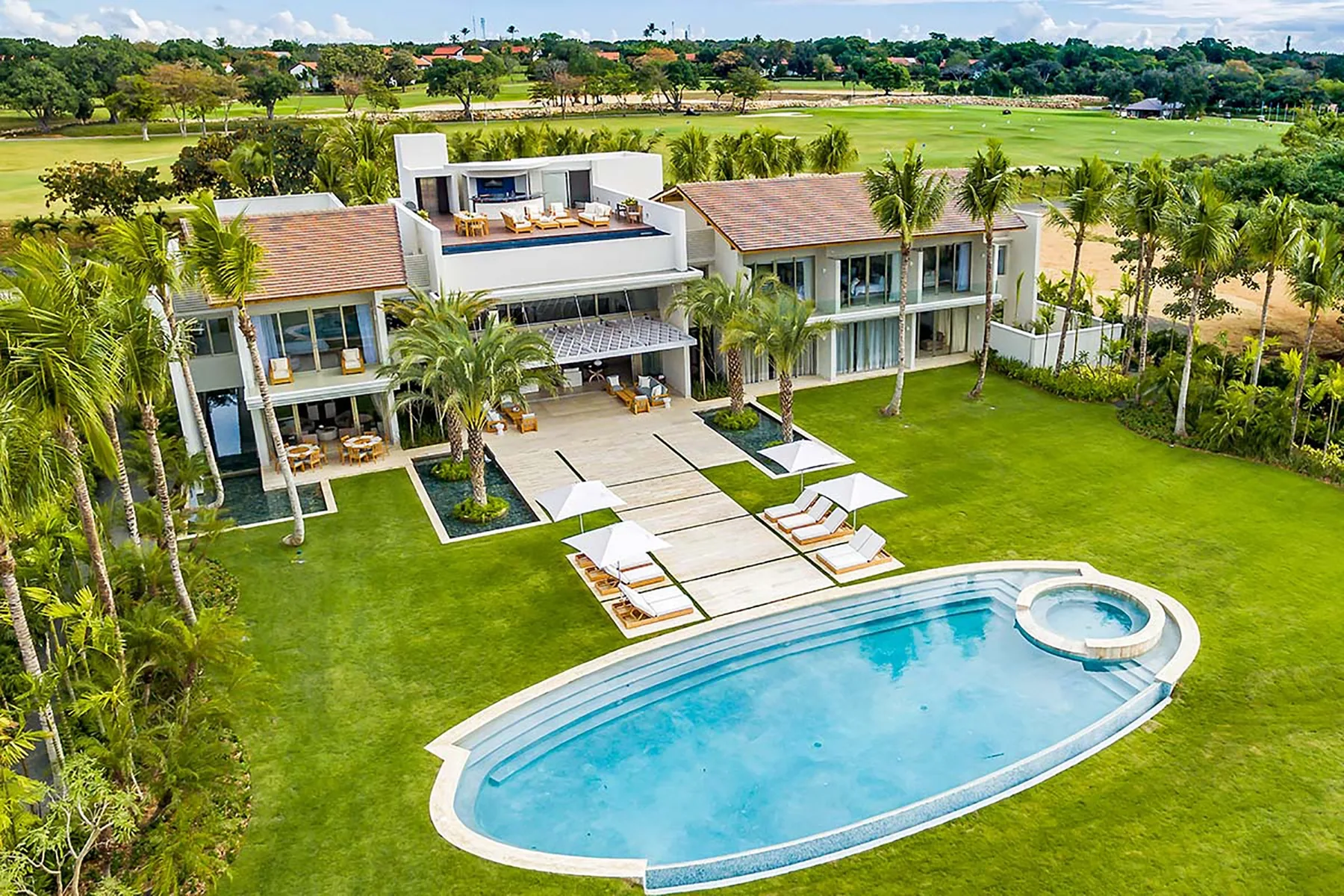 Una casa ajardinada y un césped dan a una piscina curva.