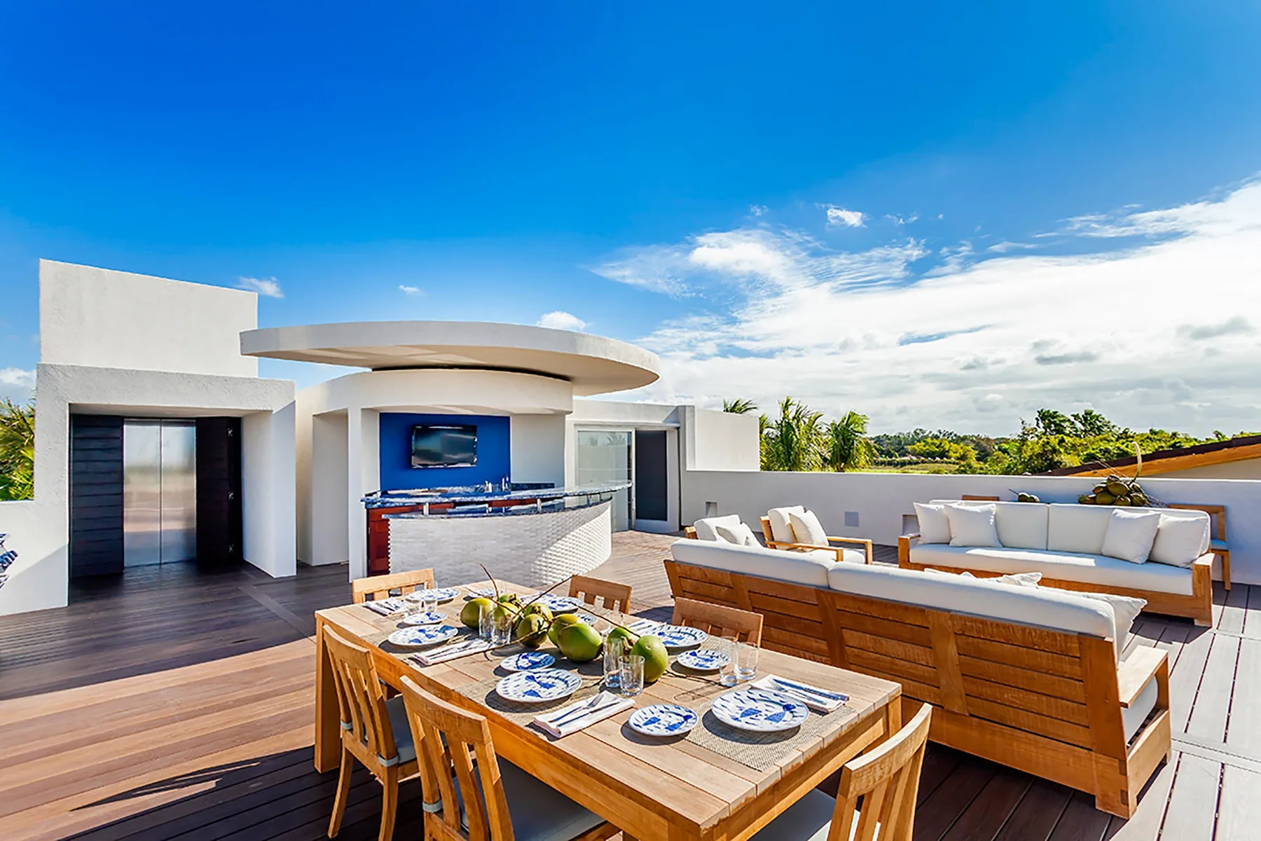 Una zona de comedor y descanso en una terraza, con mesa de madera y asientos al aire libre.