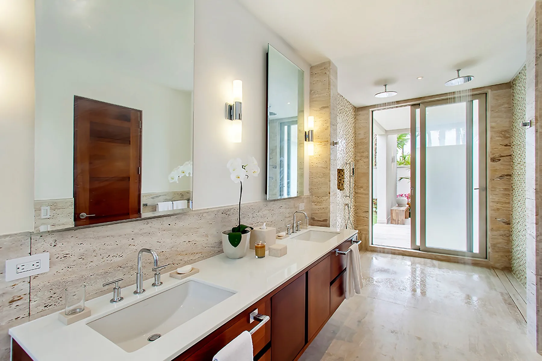 Un baño luminoso con un lavabo largo y una ducha con mampara de vidrio.