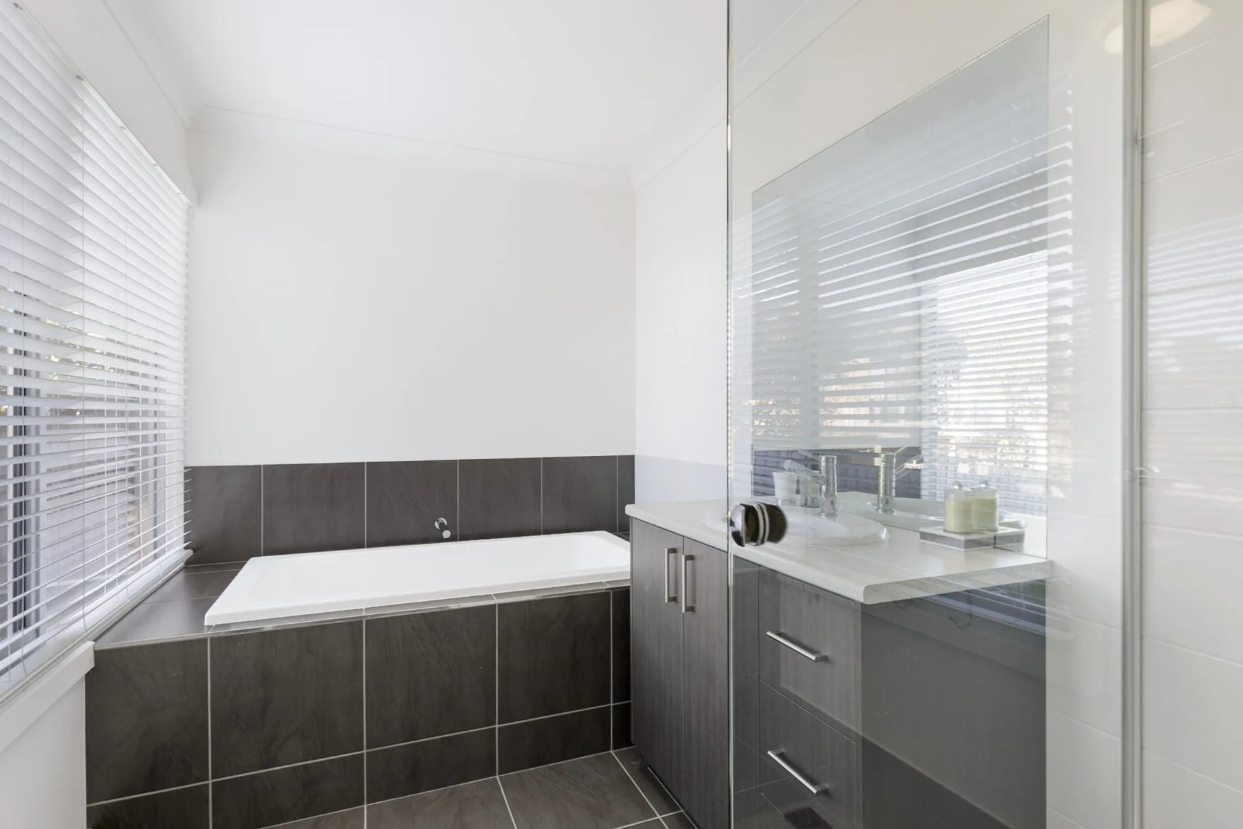 A modern bathroom with a bathtub and a vanity beside a large mirror.