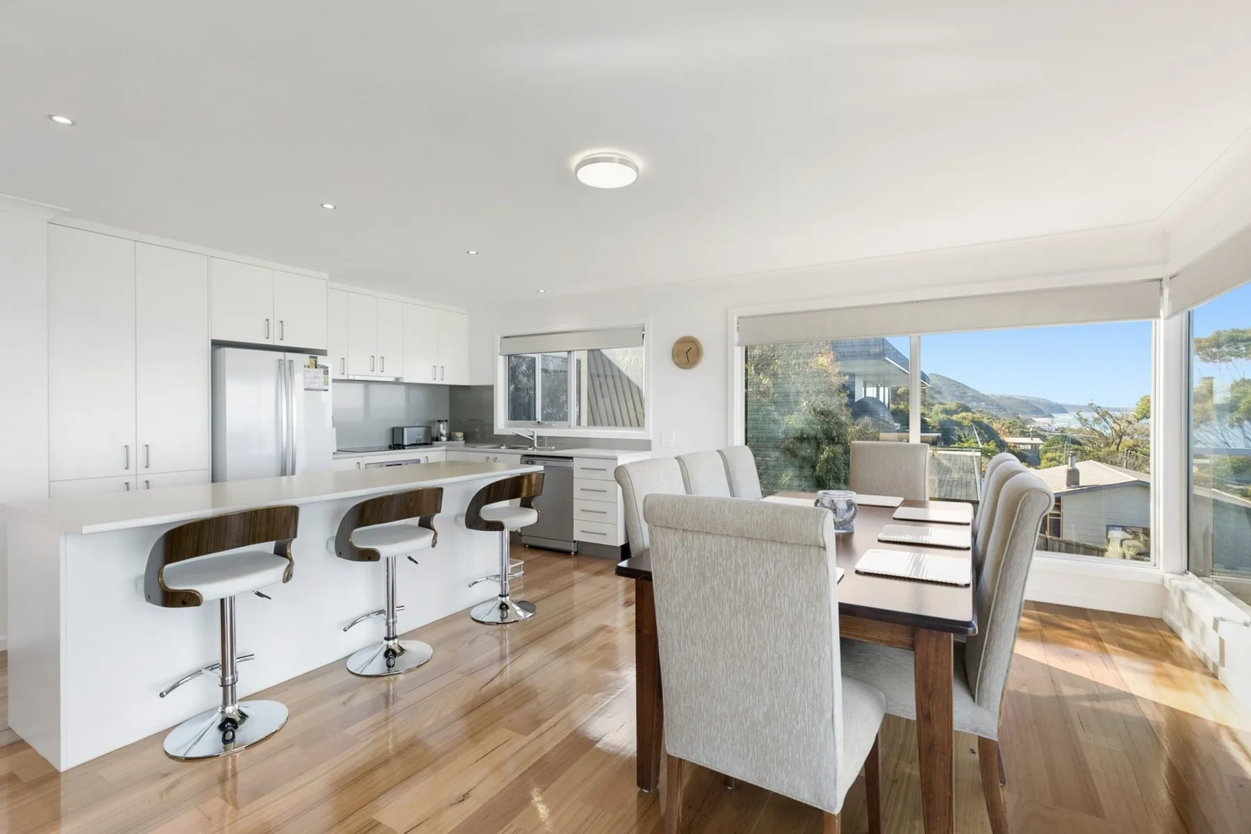 A bright dining area with a table beside large windows and a kitchen island.