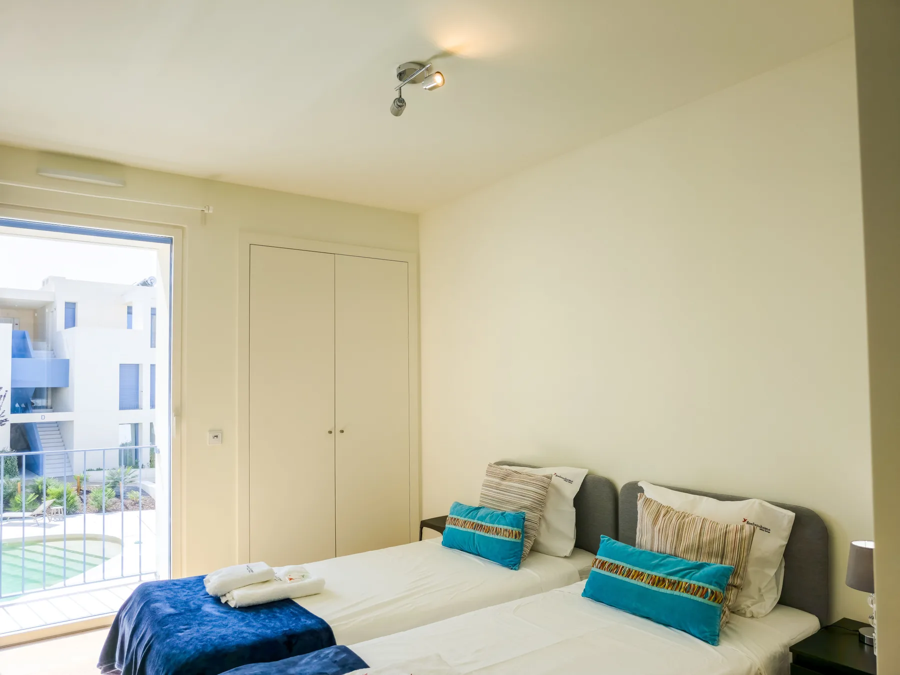 Un dormitorio luminoso con camas individuales y una puerta de cristal corredera.