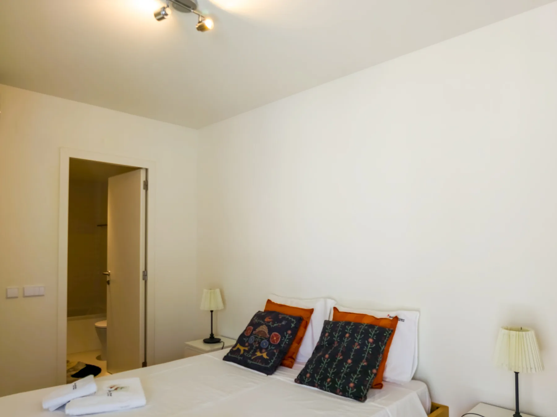Dormitorio con una cama tendida y lámparas de noche.