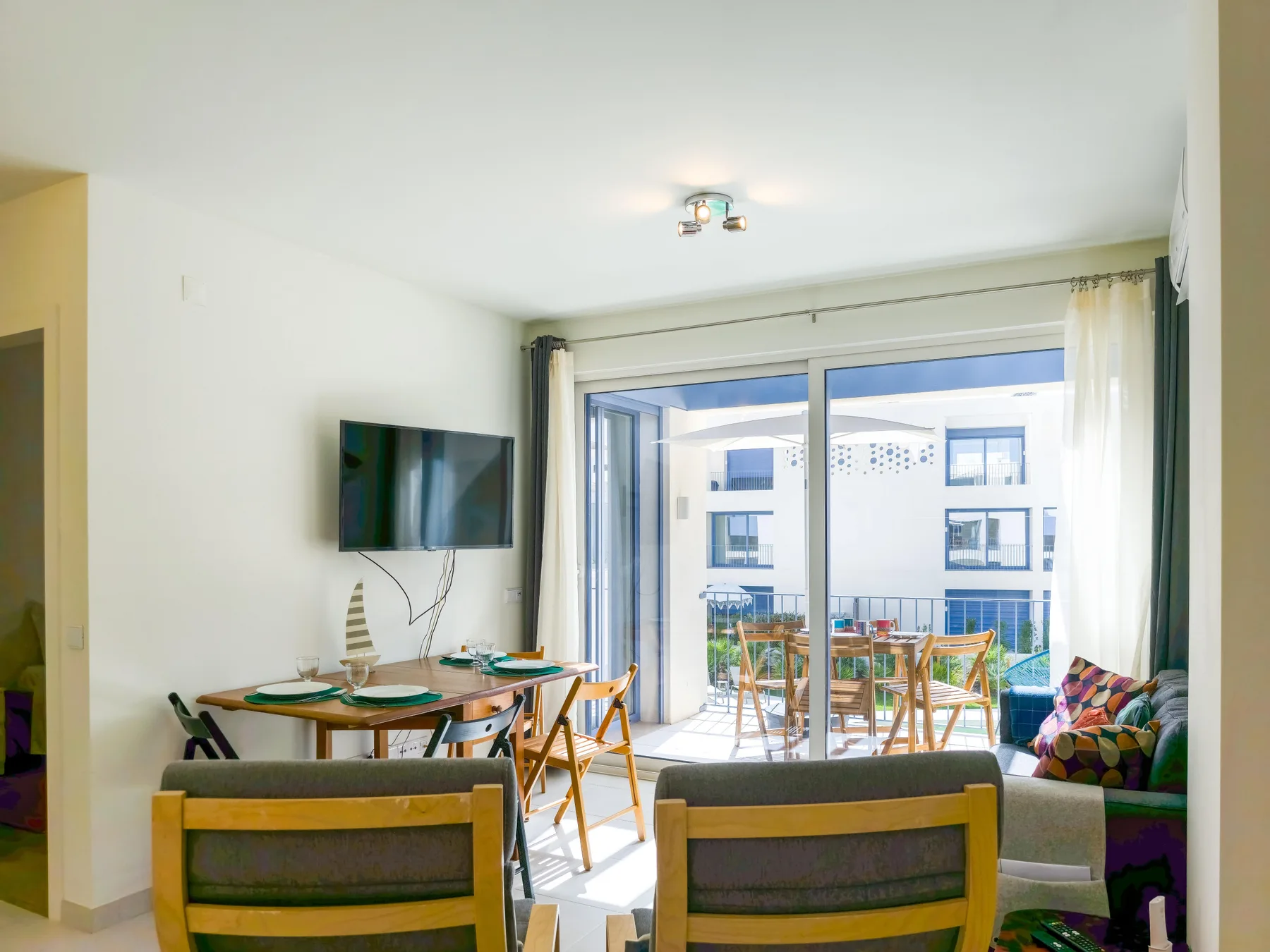A living and dining area opens onto a balcony through large sliding glass doors.