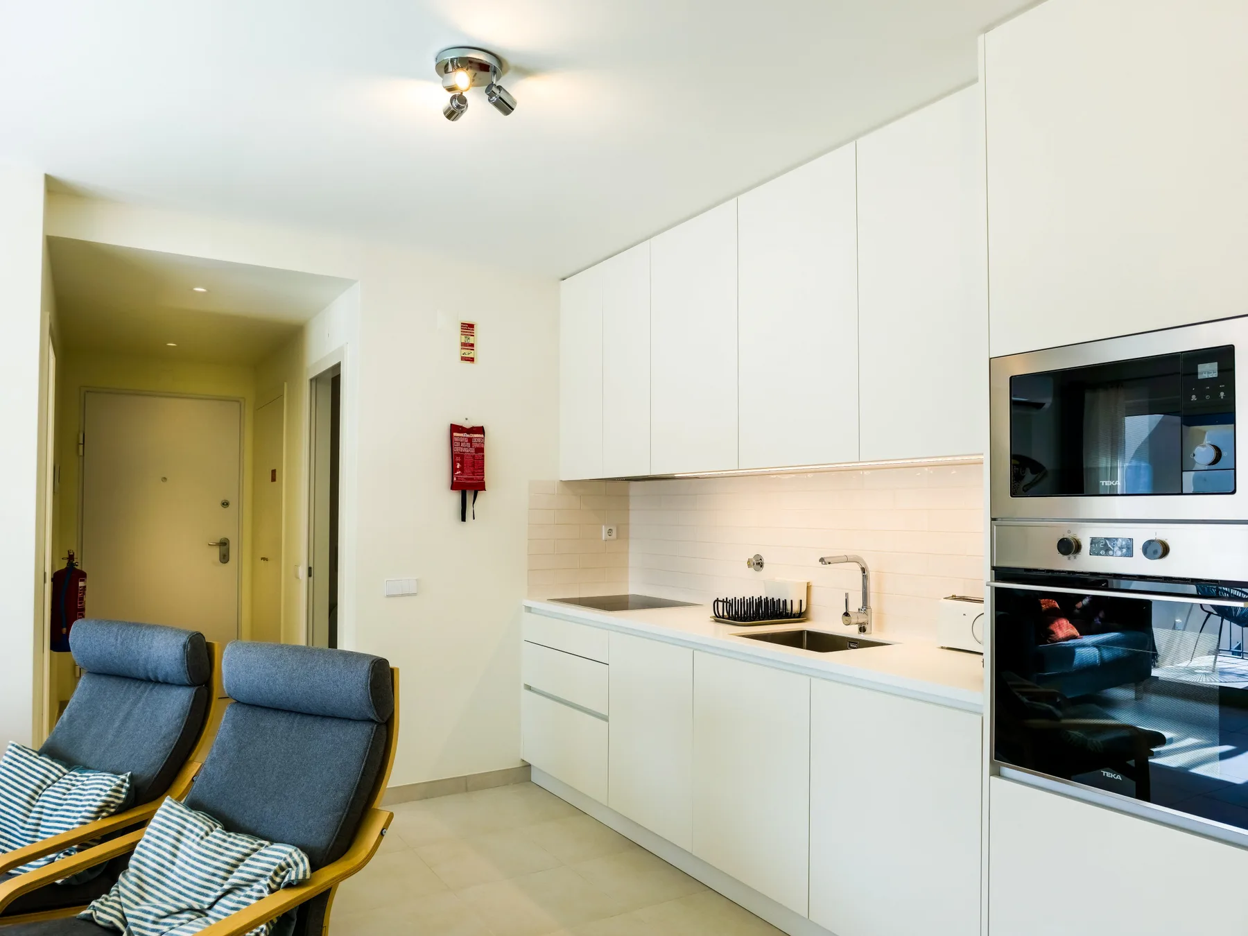 Una cocina luminosa con electrodomésticos integrados y asientos en primer plano.