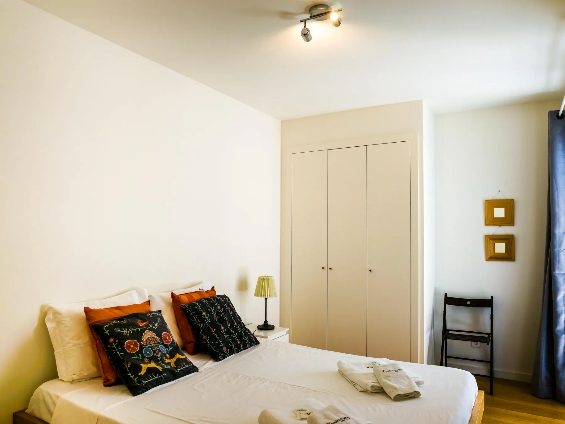 A bedroom with a bed, bedside lamp, and wardrobe.