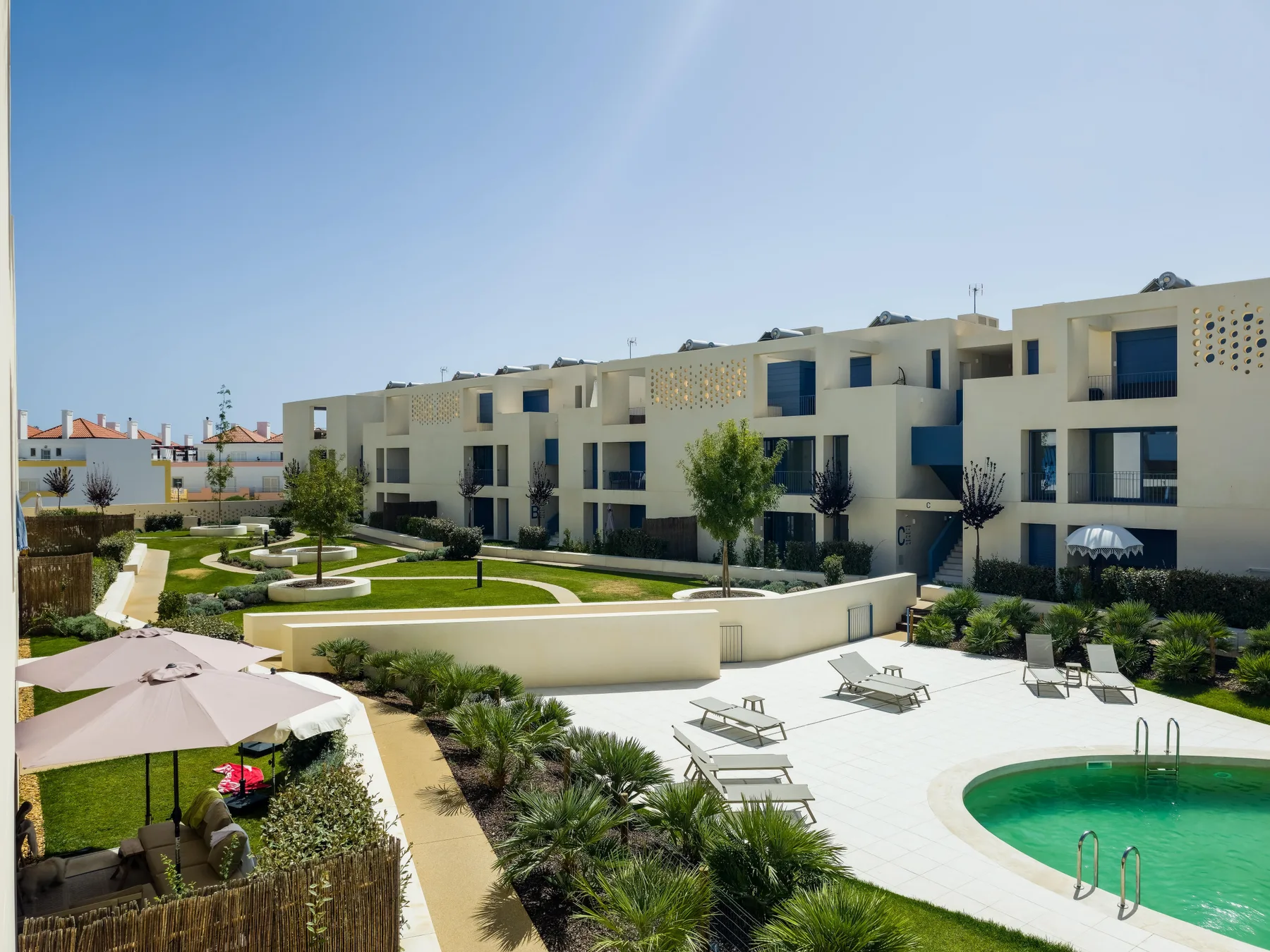 Apartment buildings surround an outdoor swimming pool and landscaped courtyard.