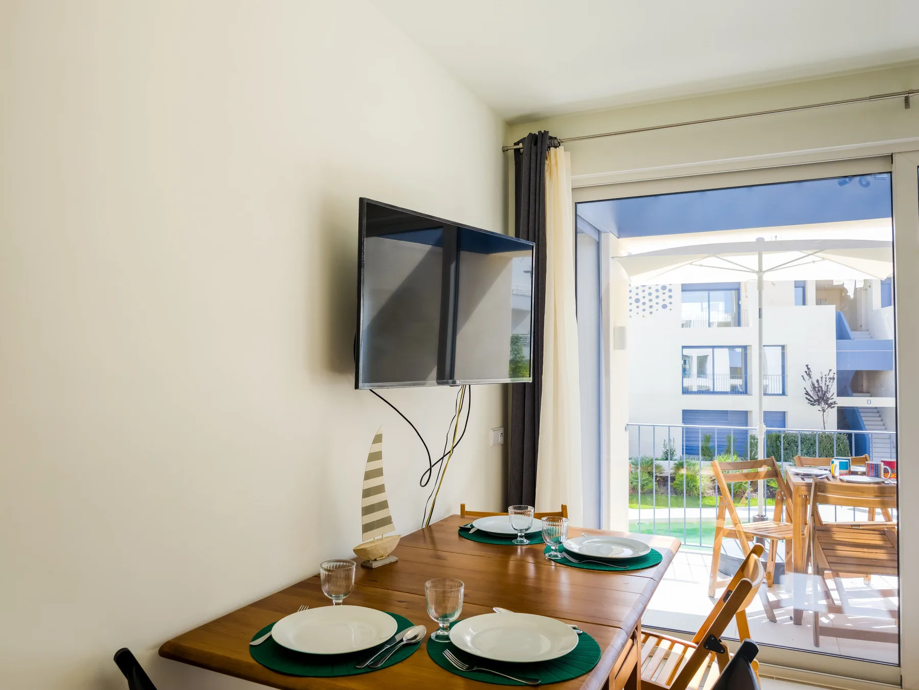 Dining area with a wooden table beside sliding glass doors opening onto a balcony.