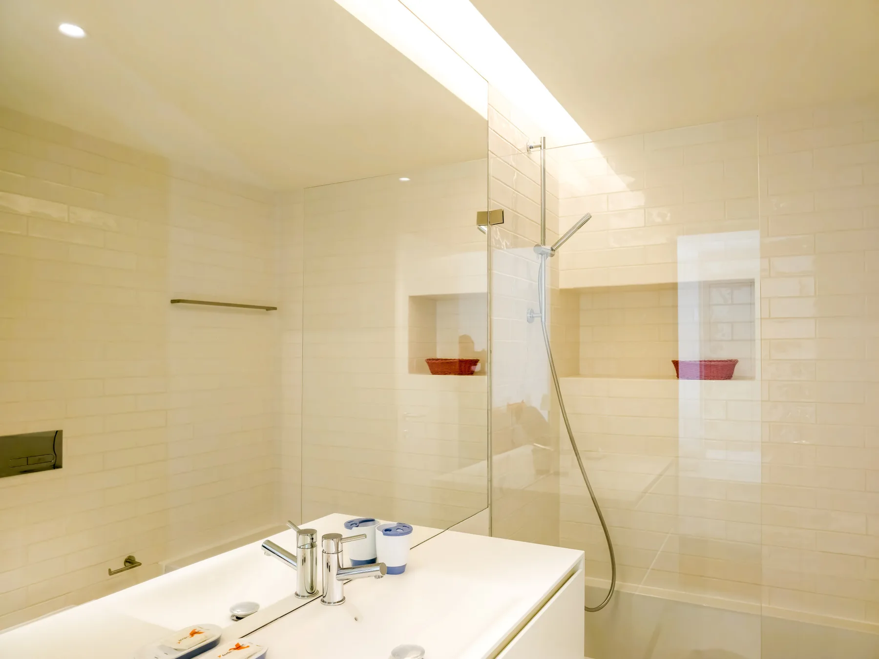 A tiled bathroom with a shower and a white sink counter.