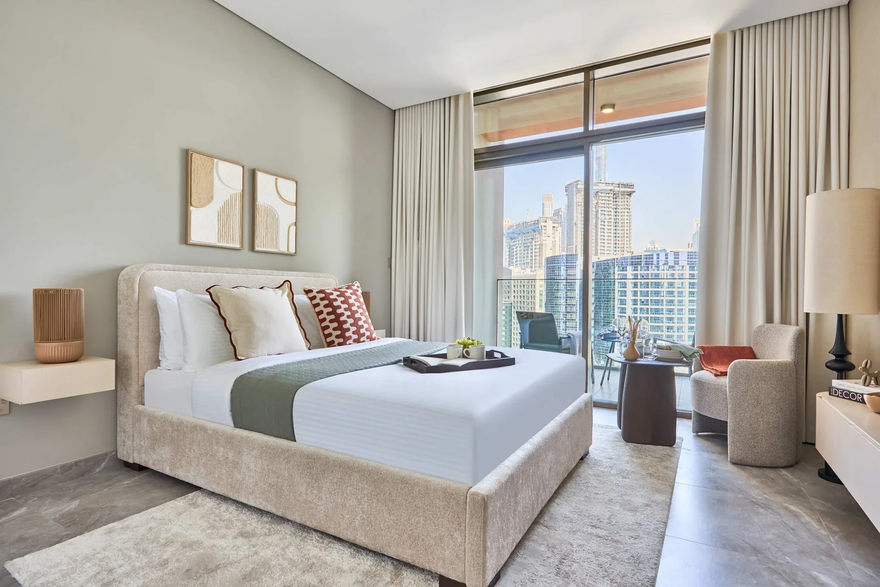 Un dormitorio con una cama grande junto a ventanales con vistas a edificios de la ciudad.