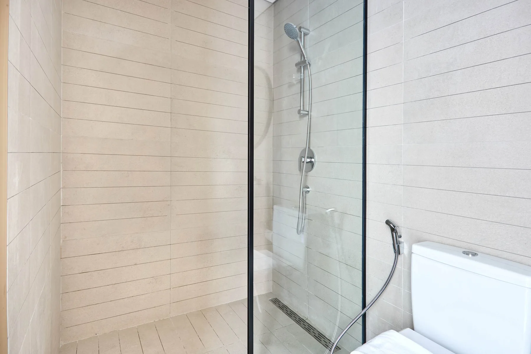 Un baño alicatado con ducha de cristal e inodoro.