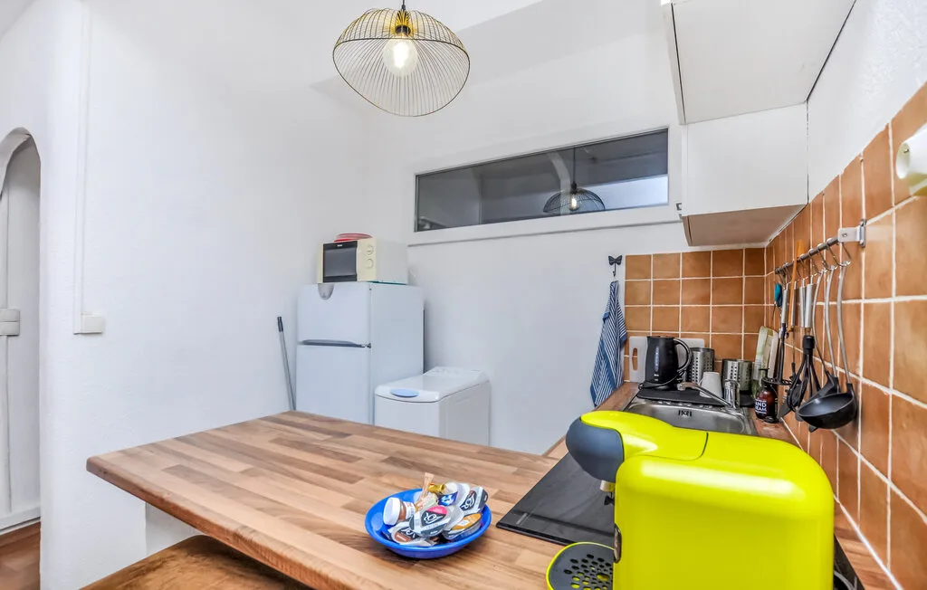 Una cocina con una encimera de madera, un refrigerador y una cafetera amarilla.